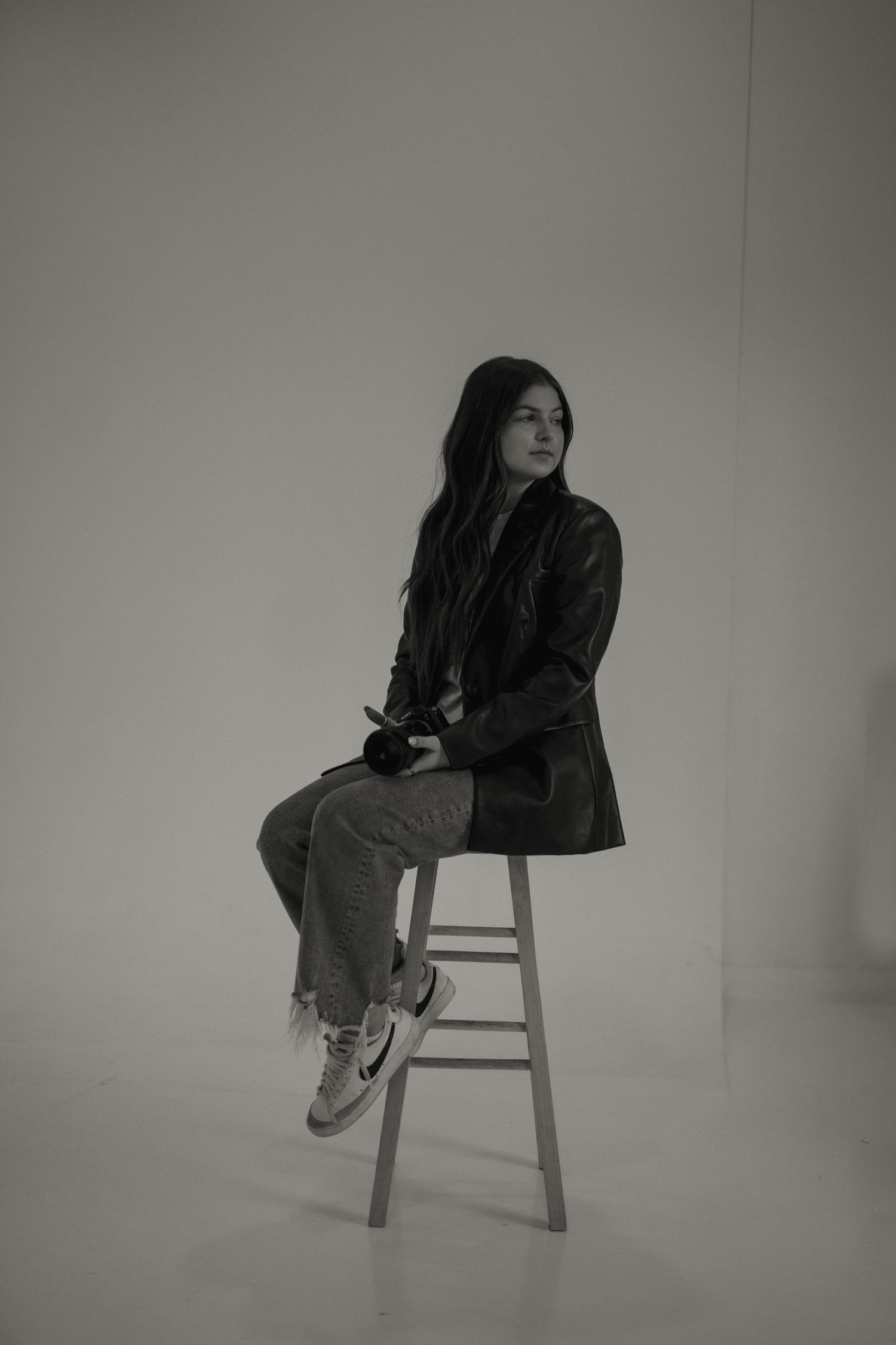 Artistic black and white portrait series of person posed on wooden chair.