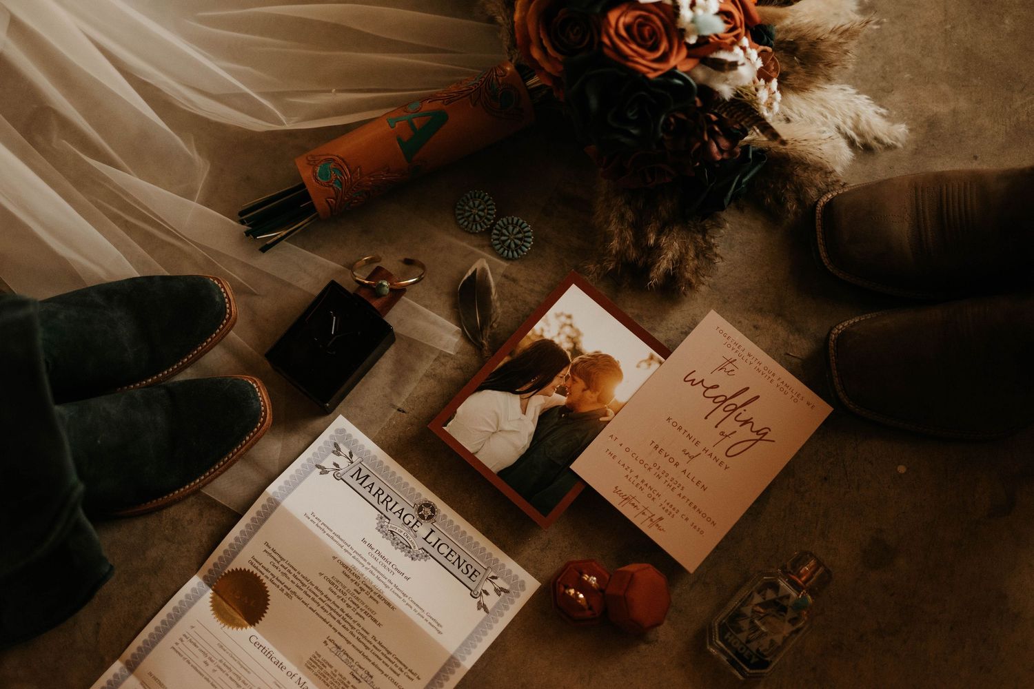 Wedding details flatlay with invitations, shoes, and floral elements in moody lighting.