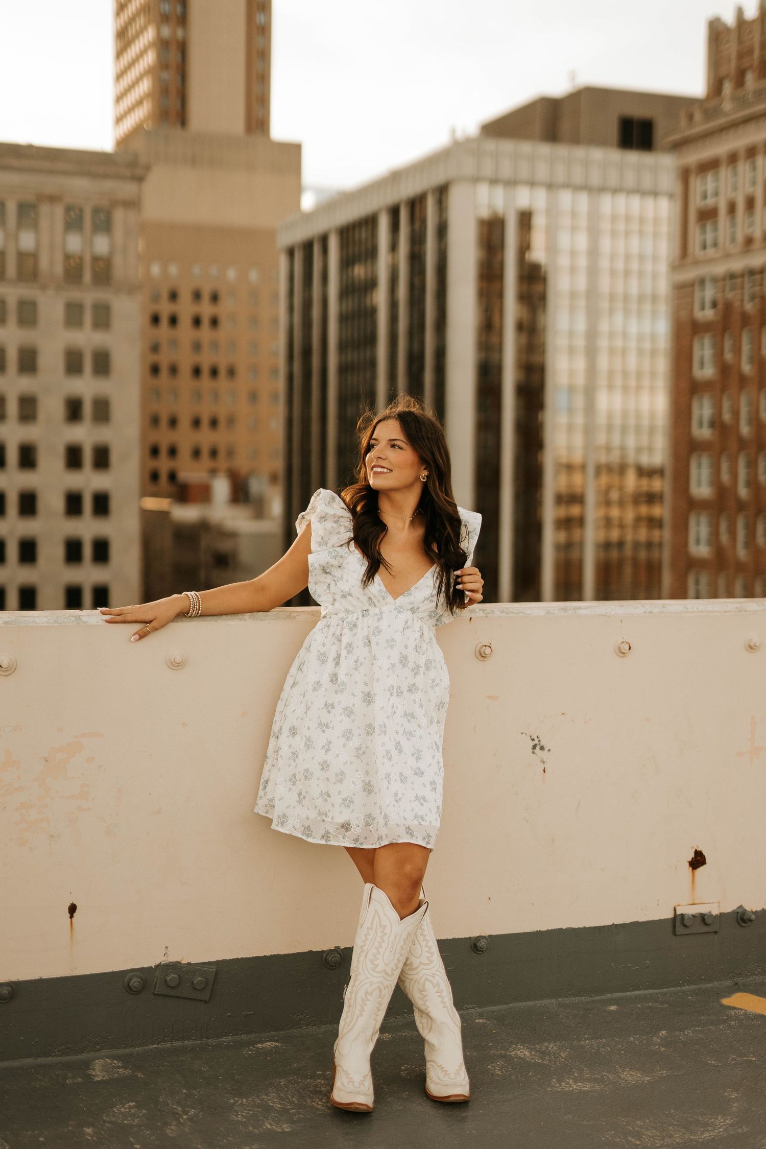 Urban rooftop fashion shoot featuring white floral dress and boots.