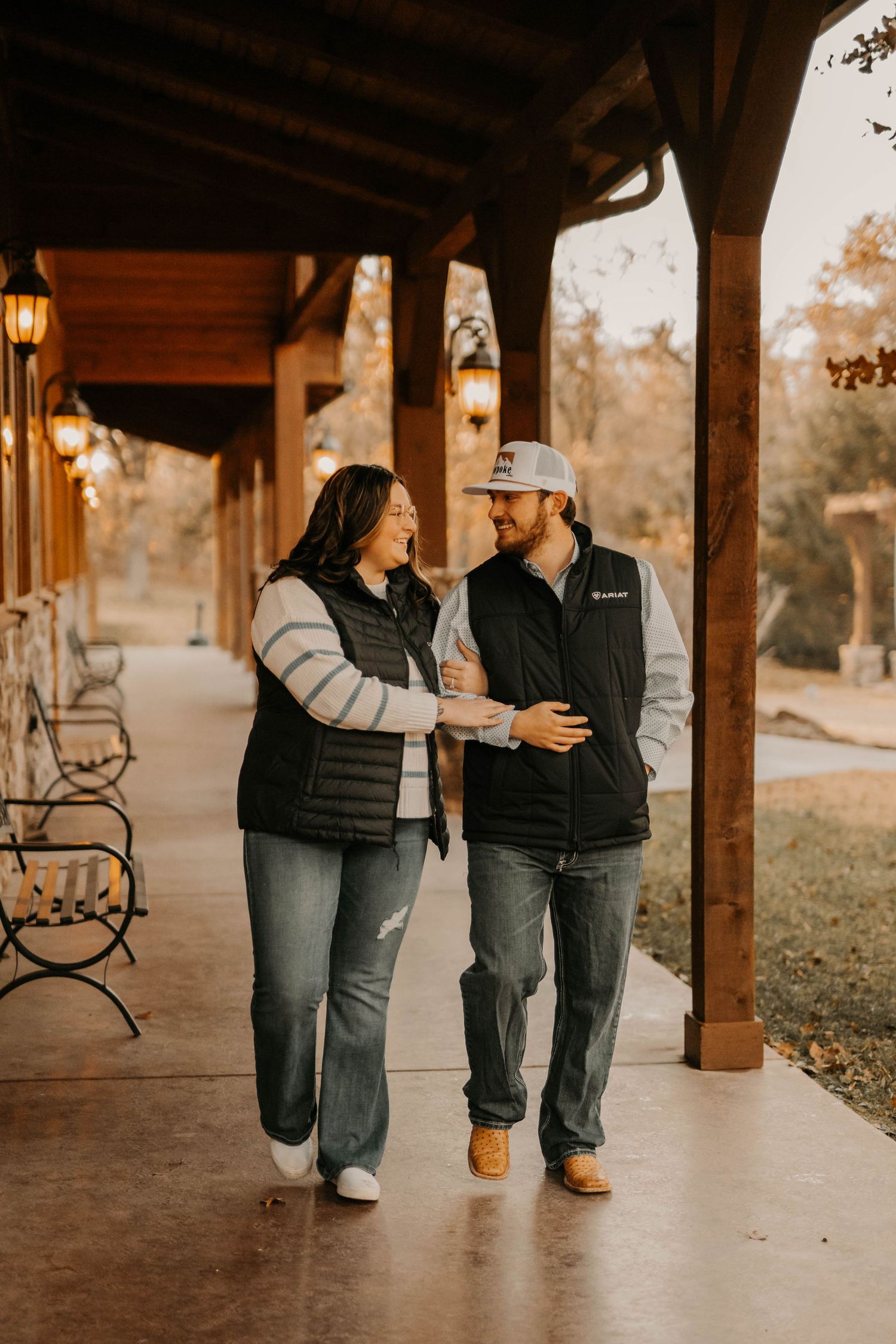 Couple walking and laughing together on covered rustic porch with lanterns.