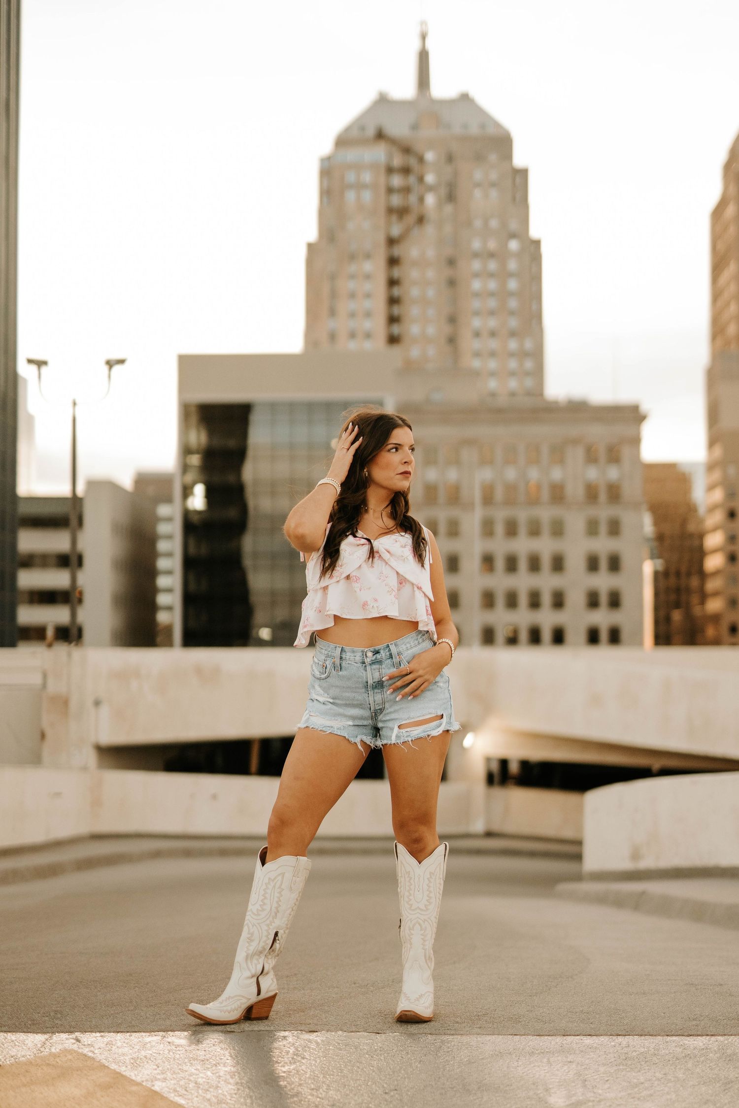Fashion portrait with city skyline background and white cowboy boots.