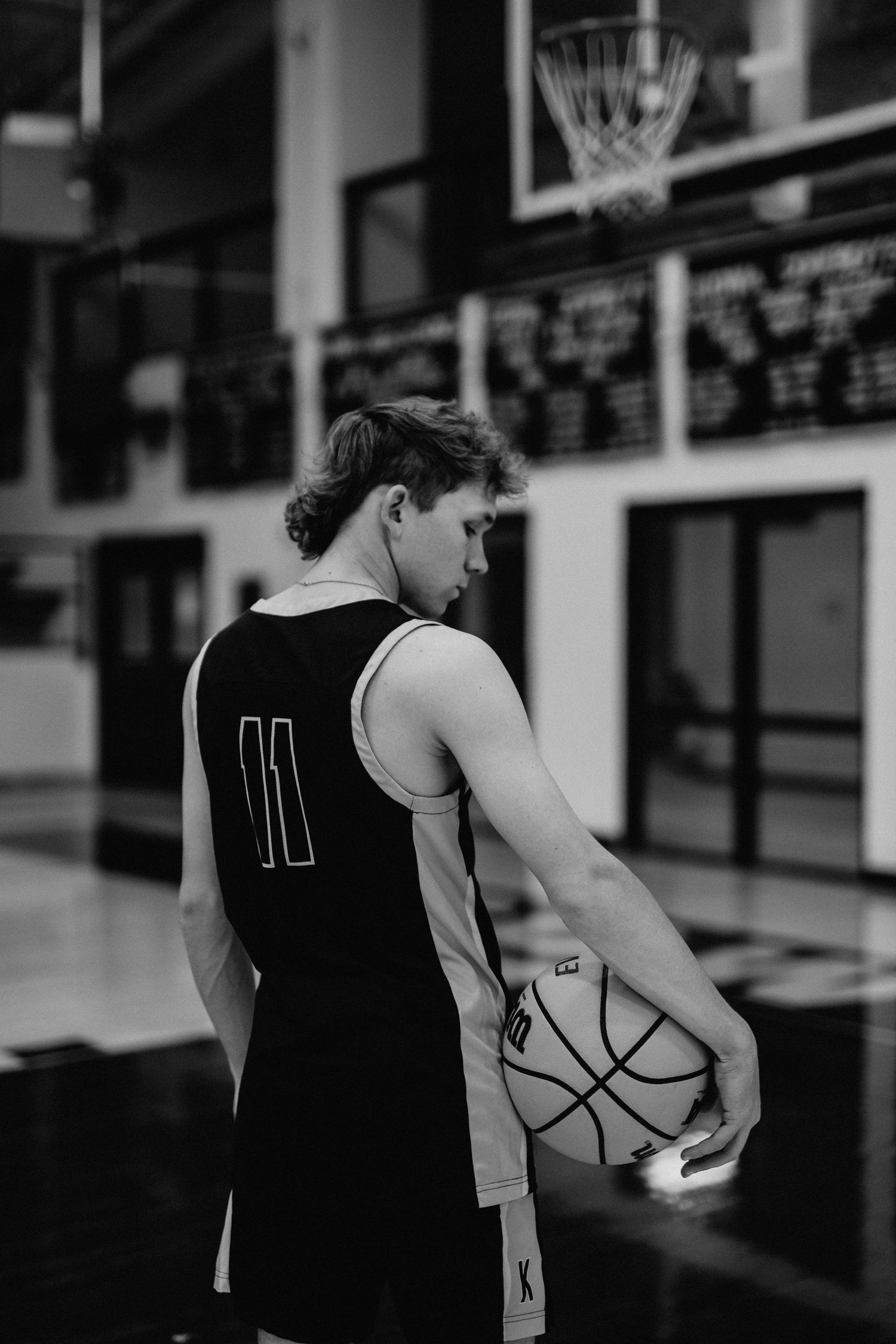 Basketball player in black jersey number 11 holding ball in gymnasium.