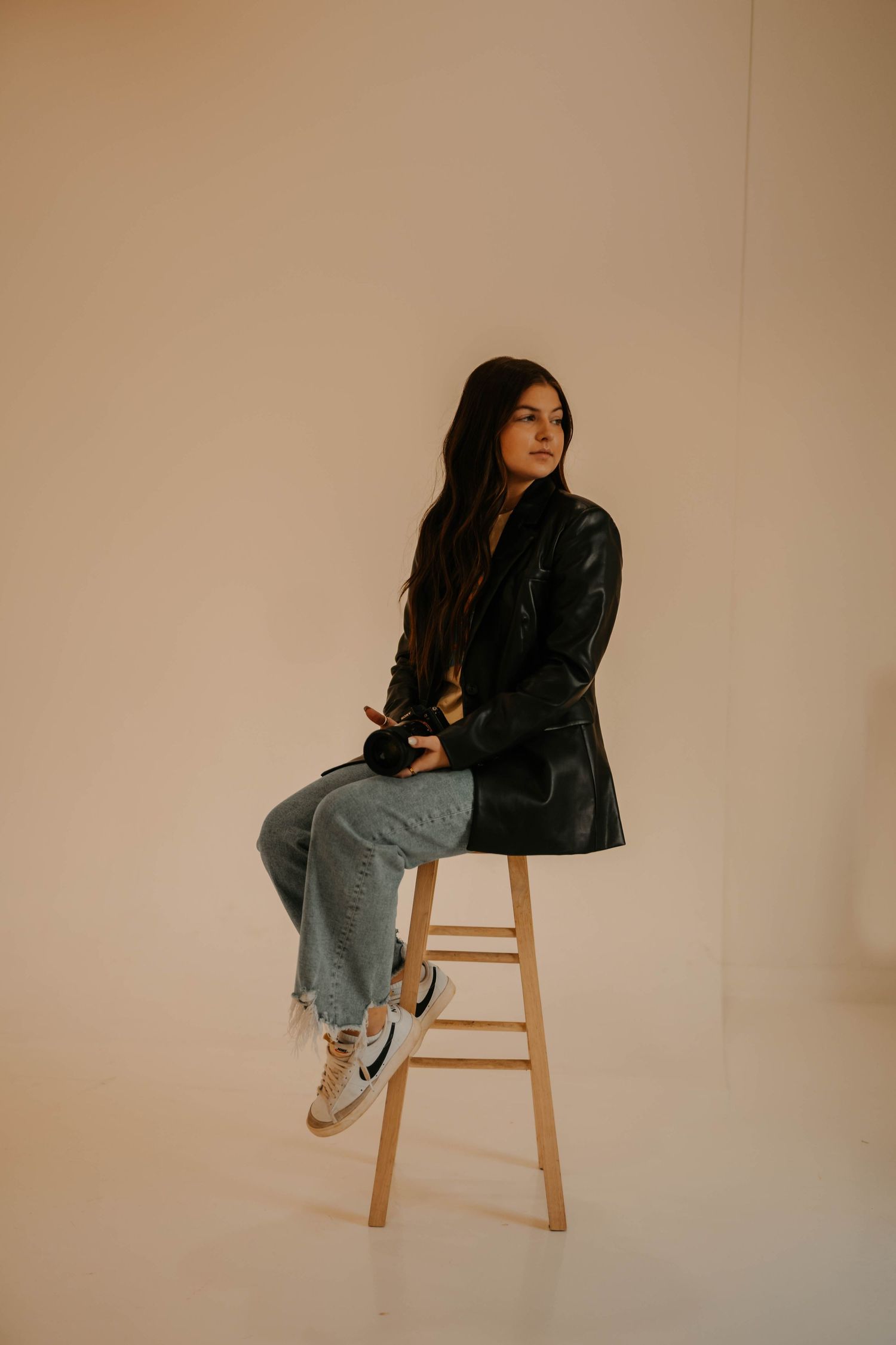 Artistic portrait series showing a person posing on a wooden stool against a neutral beige backdrop.