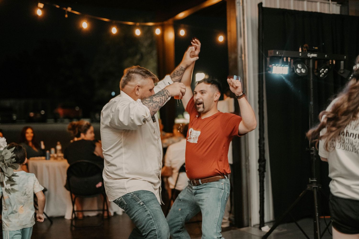 Wedding guests celebrating and dancing energetically at outdoor reception.