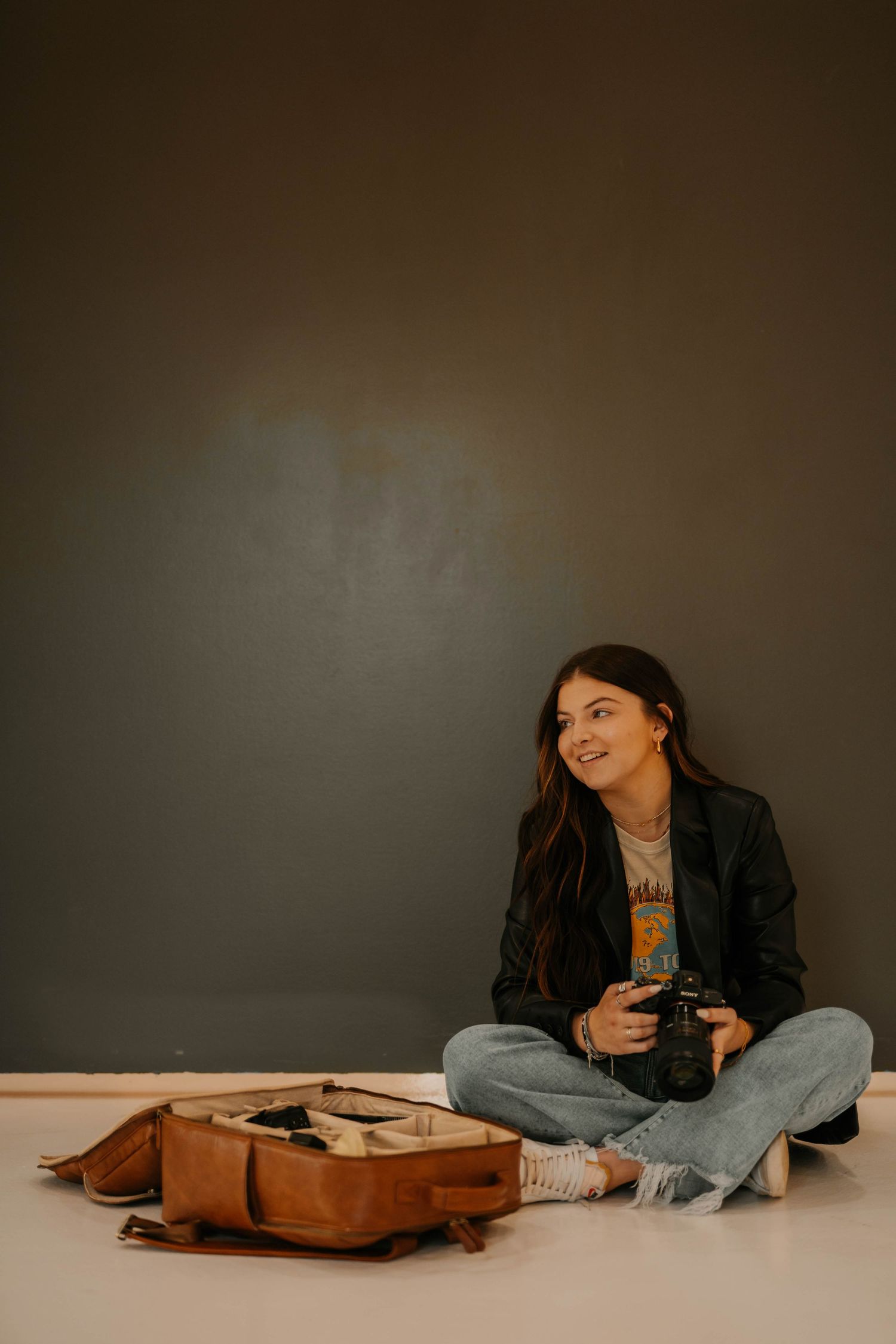 Casual lifestyle portrait session with leather jacket and jeans on beige background.