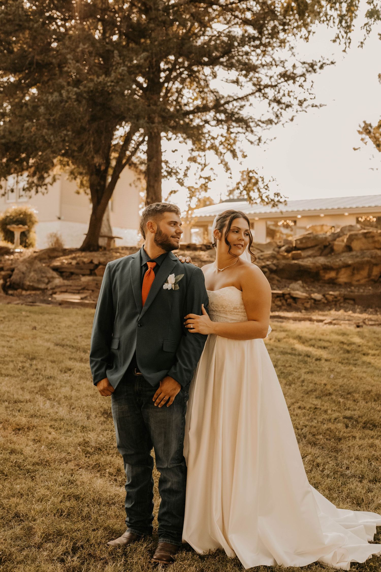 A newlywed couple poses together outdoors during golden hour.