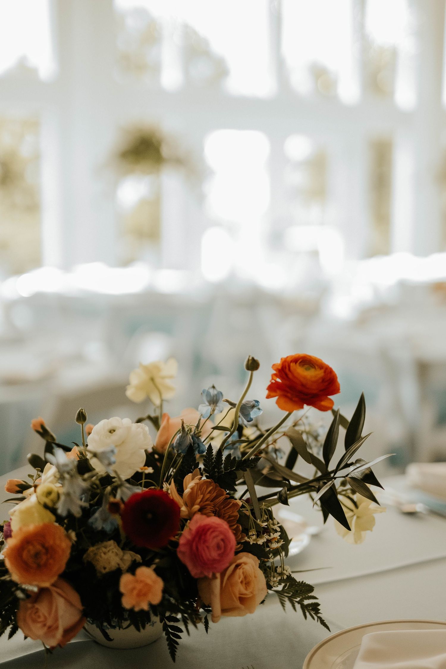 Elegant floral centerpiece with coral and white roses on wedding reception table.