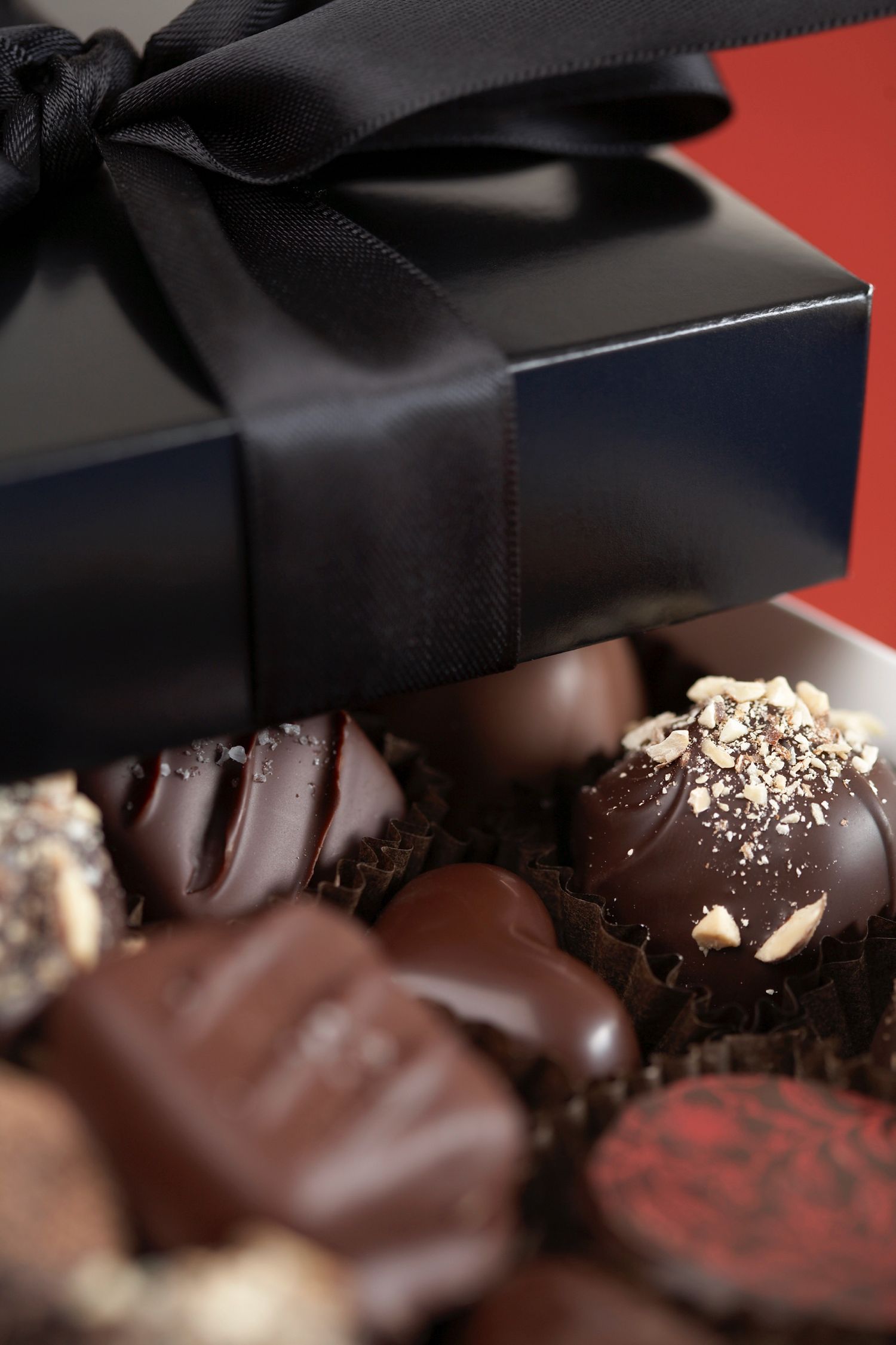 Luxury chocolate box with black ribbon containing assorted handmade truffles.