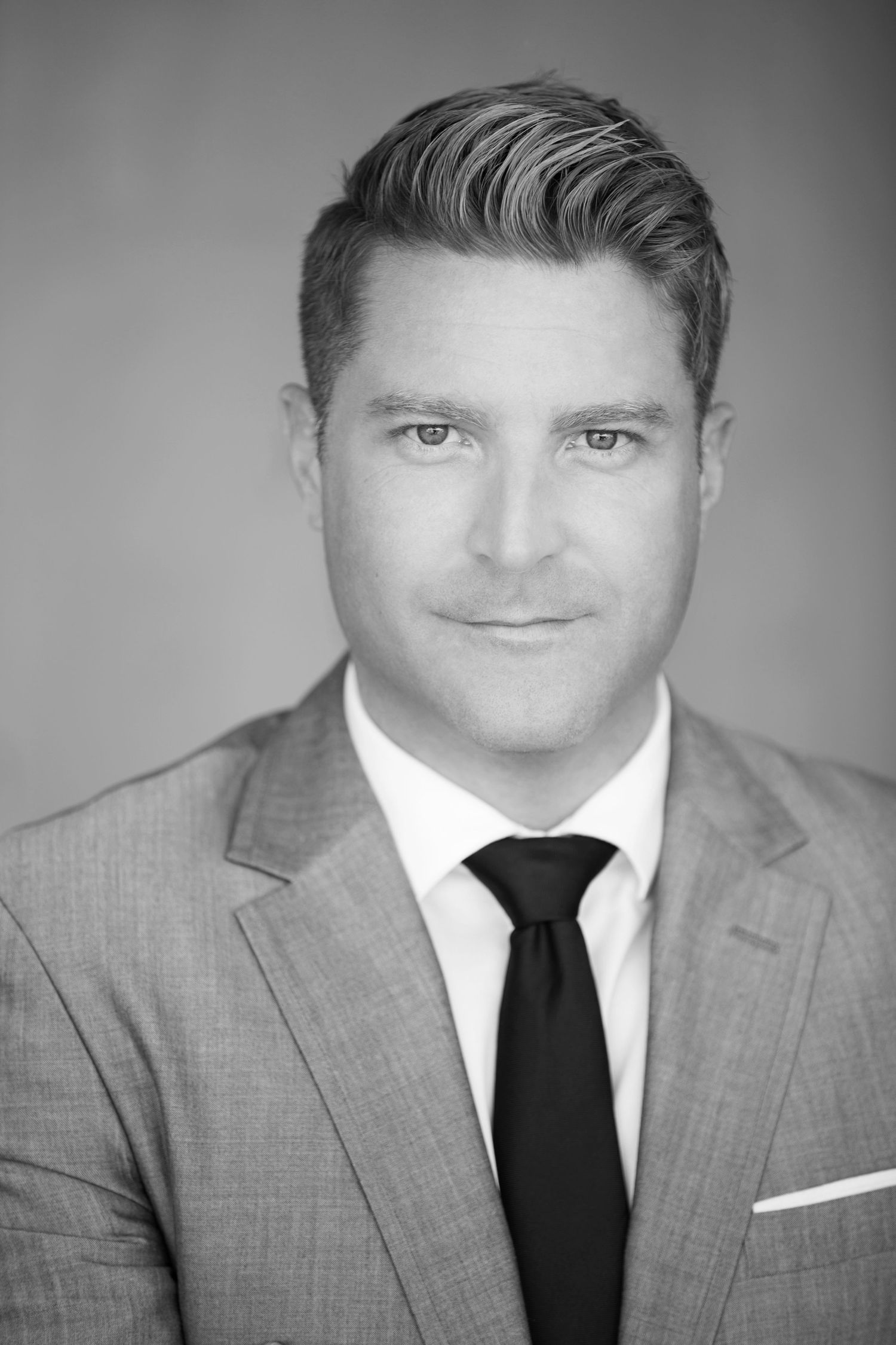 Business portrait in gray suit and black tie with professional lighting.