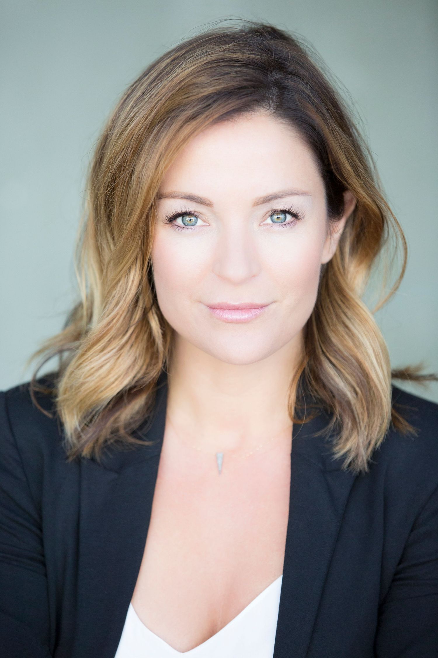 Professional headshots in black blazer against neutral background.