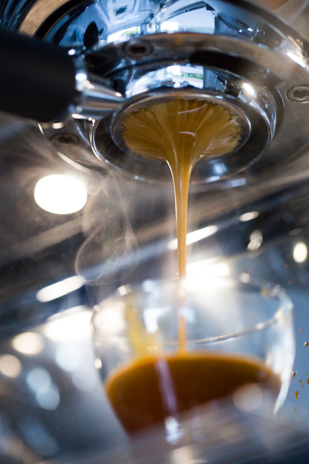 Close-up shot of espresso pouring from a professional coffee machine portafilter.