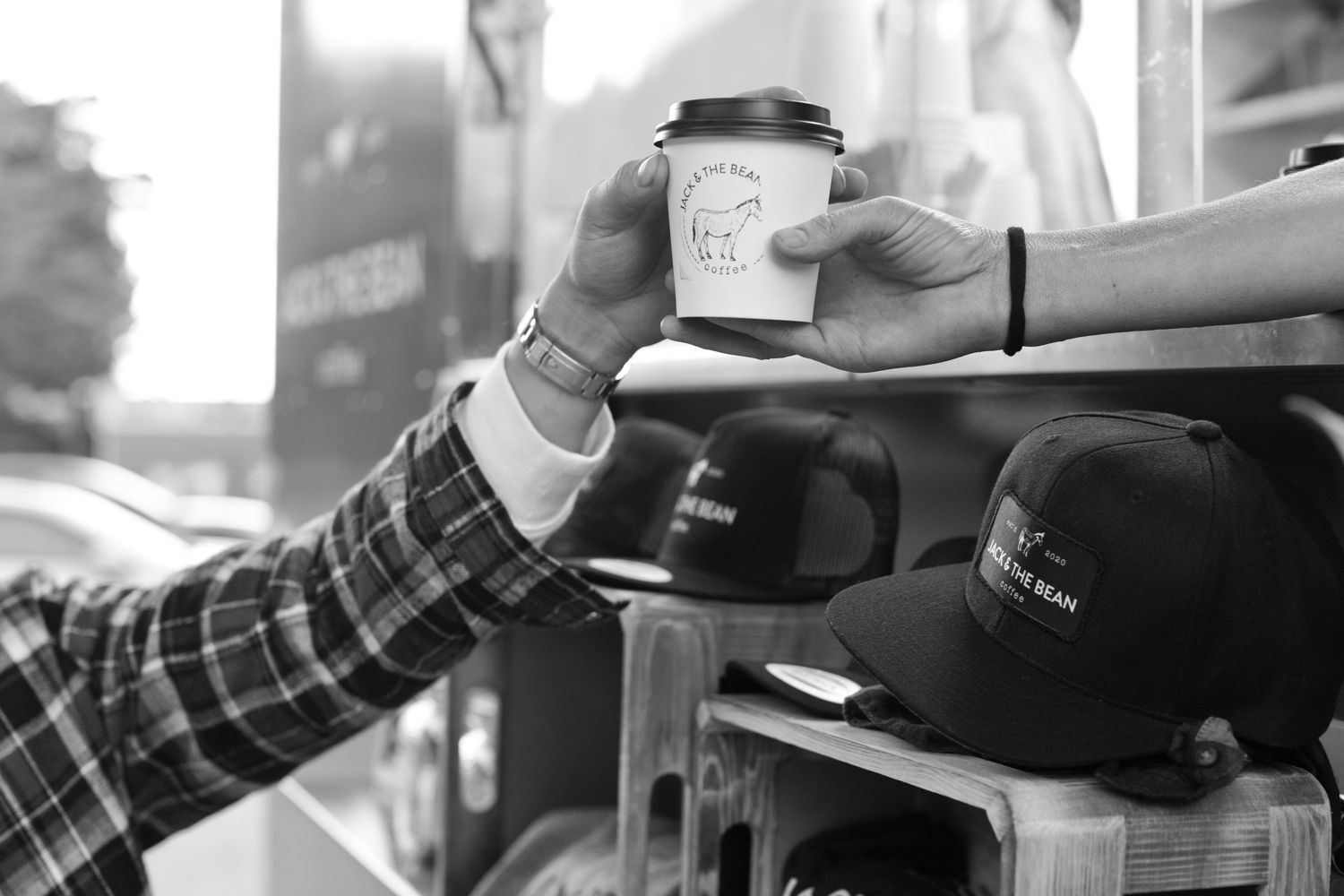 Hand reaching for a coffee cup near display of branded merchandise and hats.