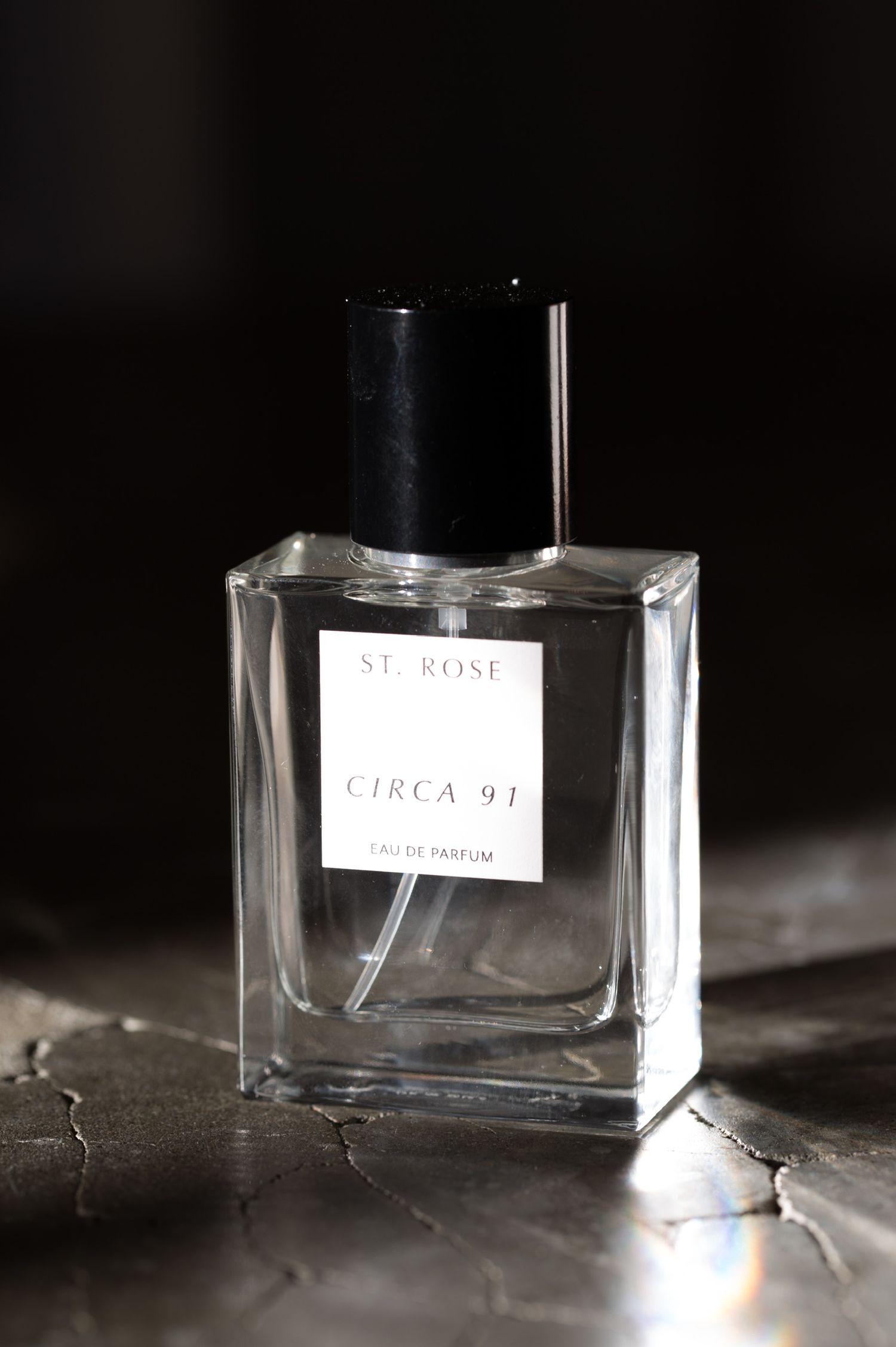 Glass perfume bottles labeled 'Circa 97' photographed in dramatic lighting.