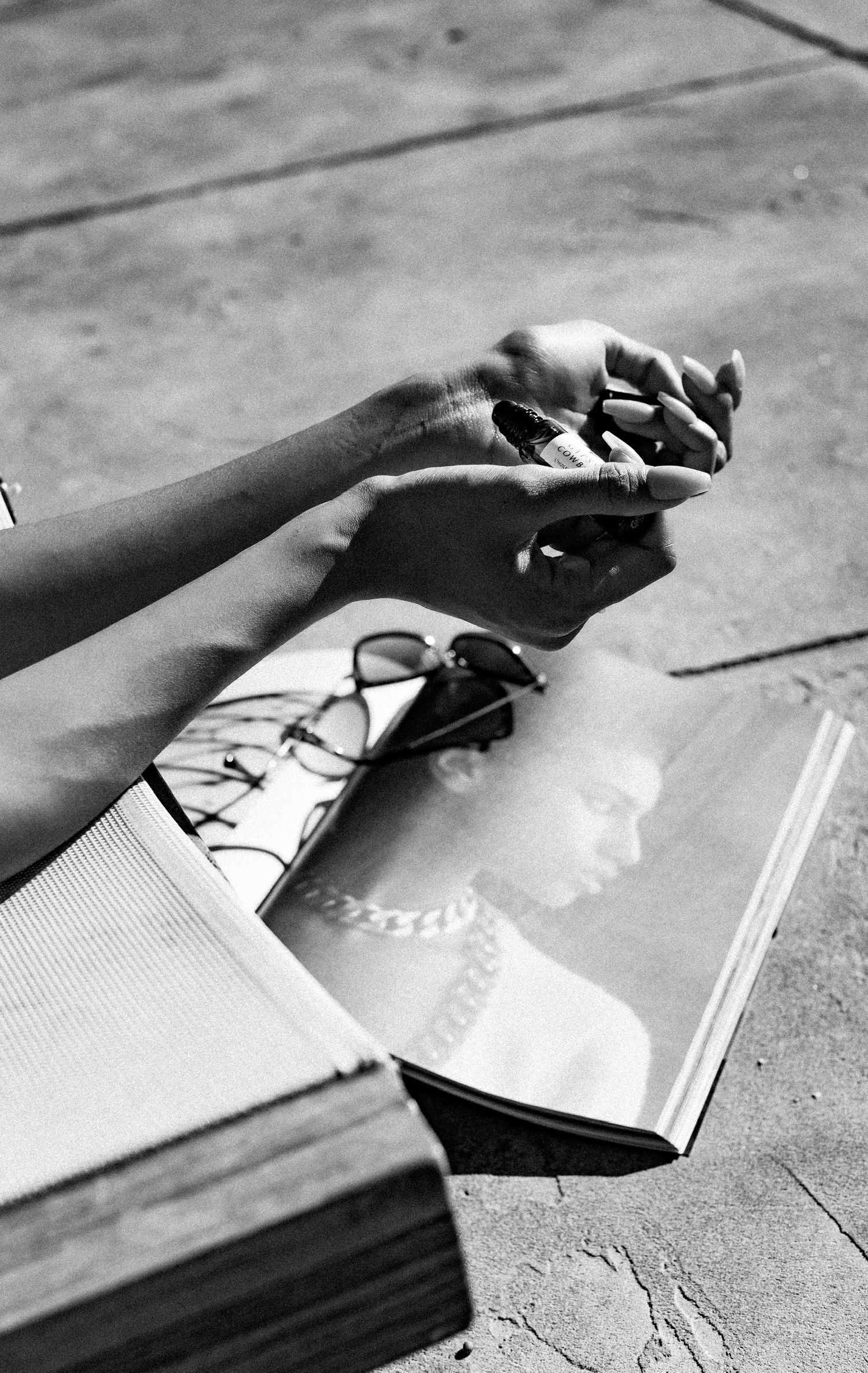 Black and white photo of hands holding small objects over an open book.