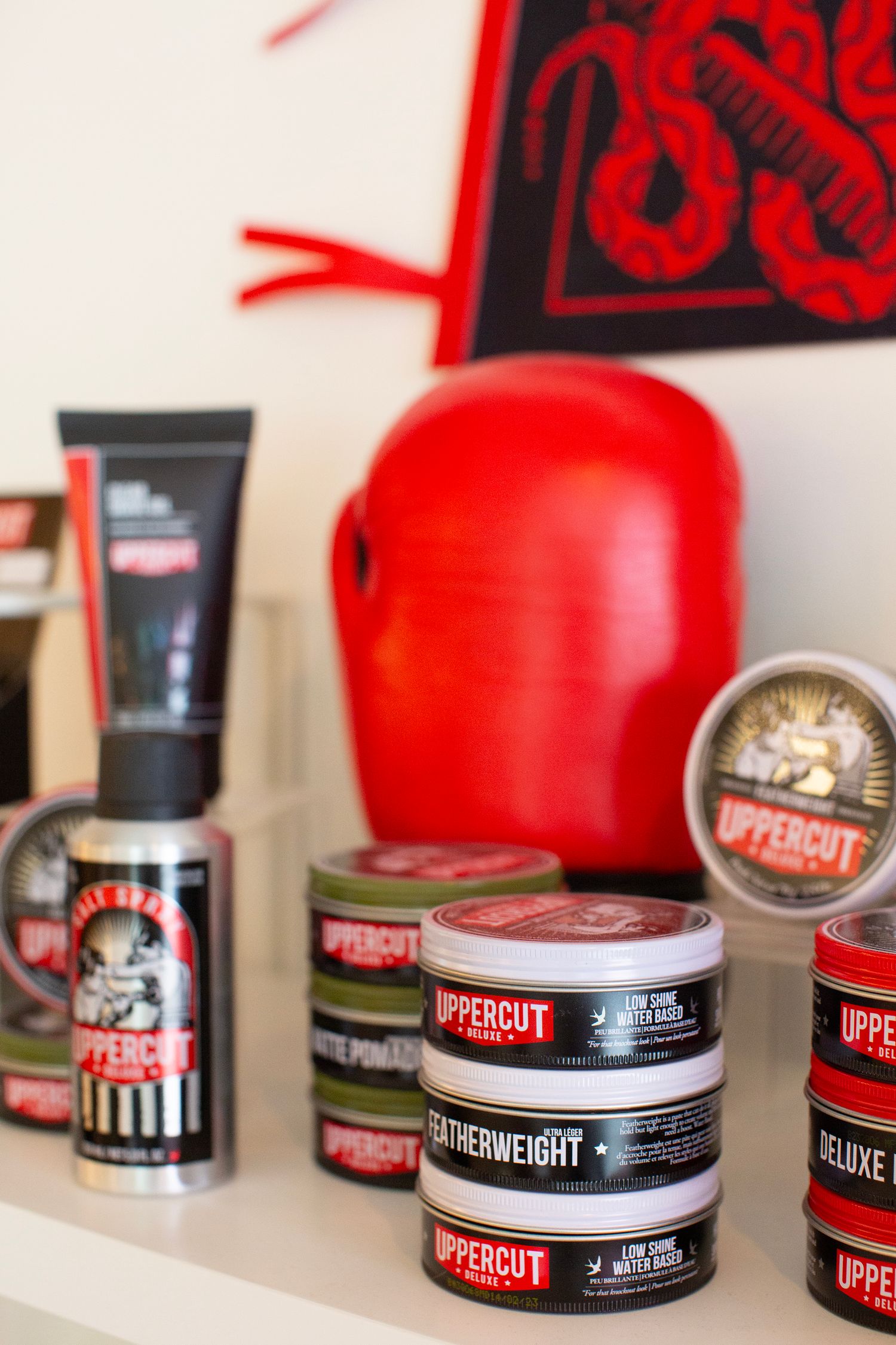 Display of red boxing equipment and grooming products including pomade tins and glove.