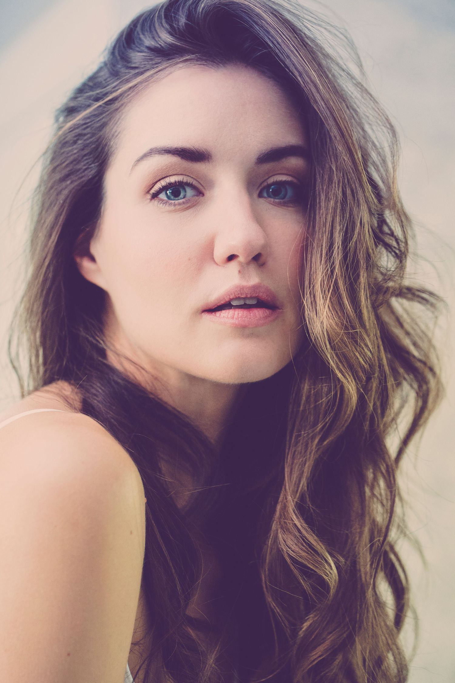 Artistic portrait with natural makeup and wavy brunette hair.