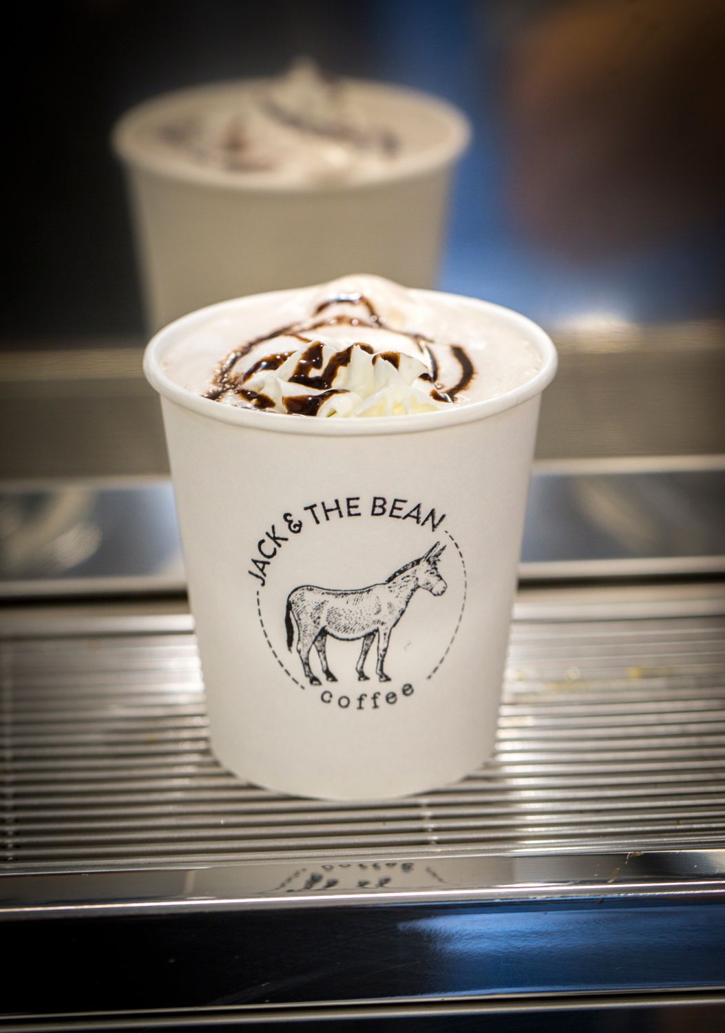 White paper cup with donkey logo filled with whipped cream topped beverage.
