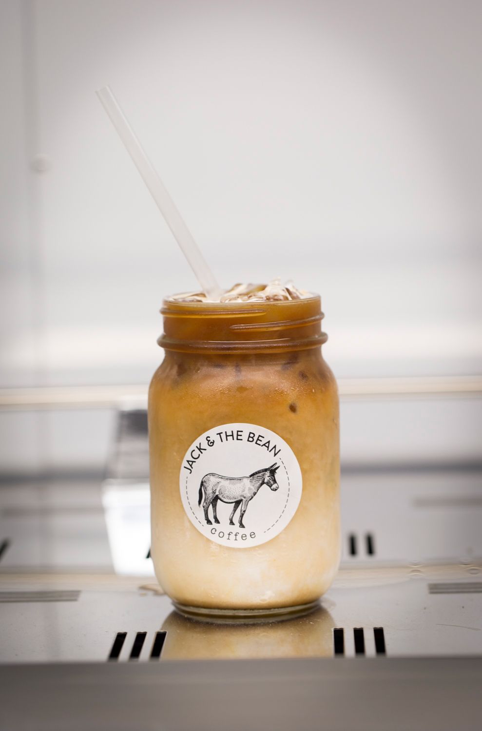 Artisanal coffee containers with horse logo branding lined up on display shelf.