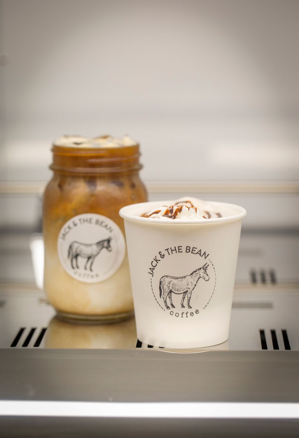 Coffee shop branded cups and containers with horse logo on white counter display.