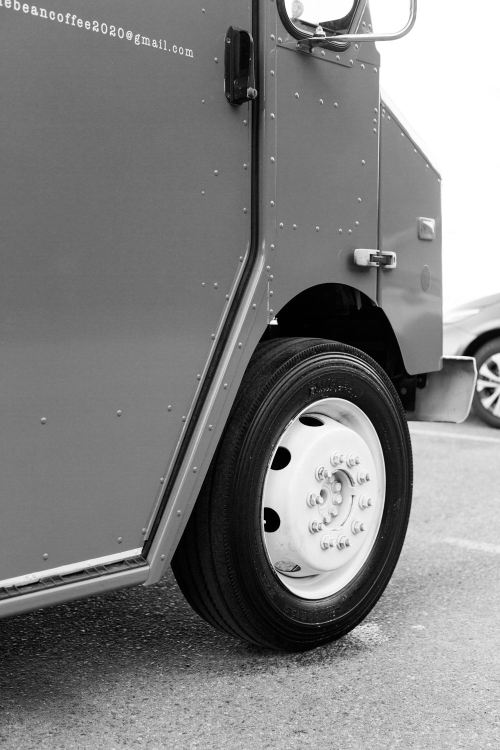 Detail shot of a commercial truck wheel and side panel in black and white.