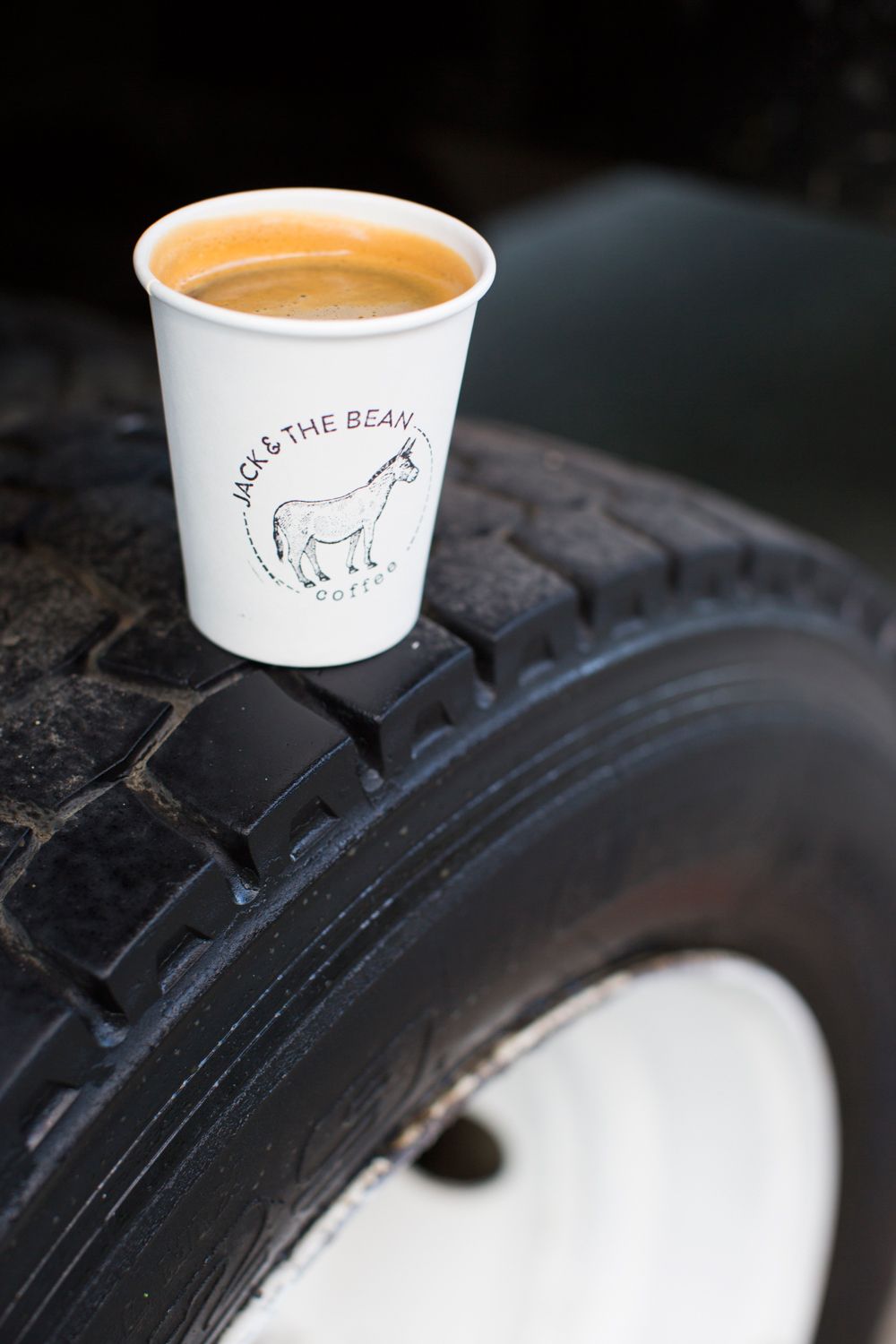 Coffee cup with donkey logo balanced on a black tire showing unique product placement.