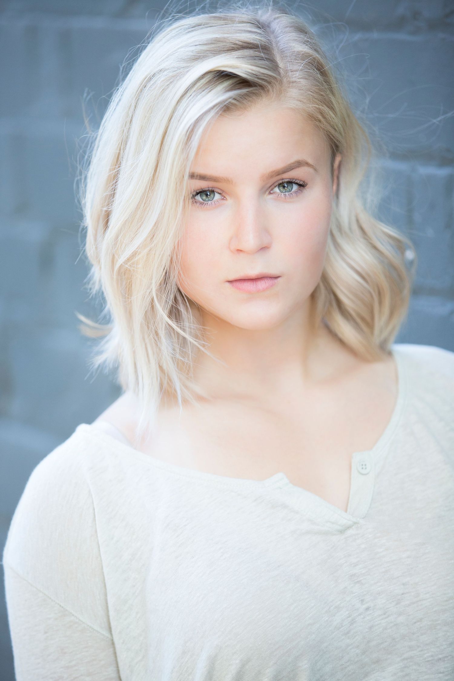 Headshot in white top against blue background with soft natural lighting.