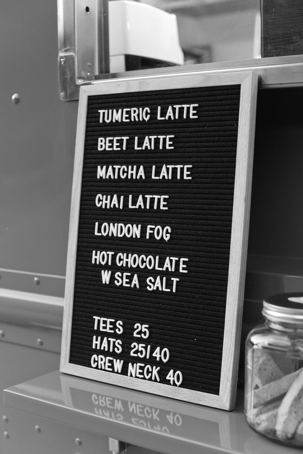Menu board displaying specialty lattes and merchandise prices at a coffee stand.