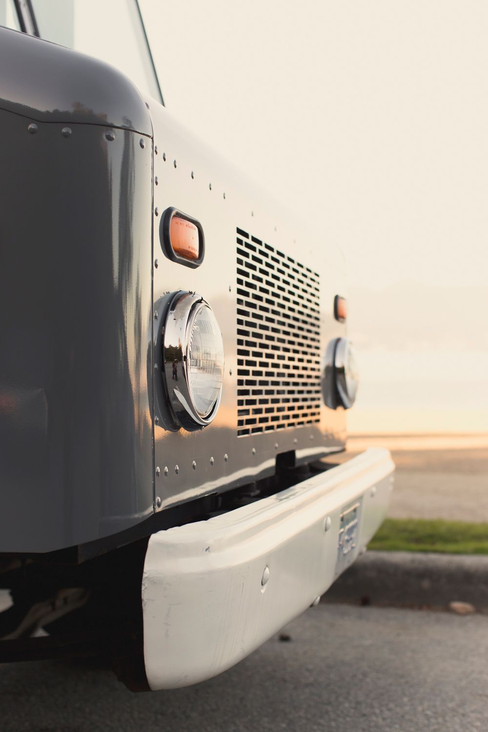Front grill and bumper detail of a commercial delivery truck in warm lighting.