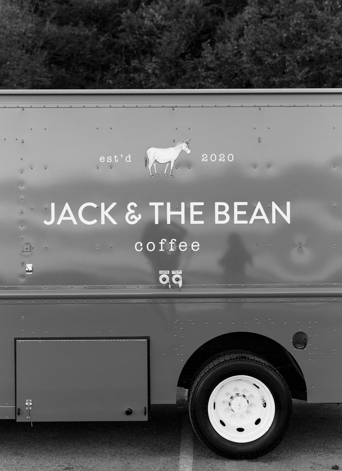 The side of a gray coffee truck showing the Jack & The Bean Coffee logo with a white cow icon.