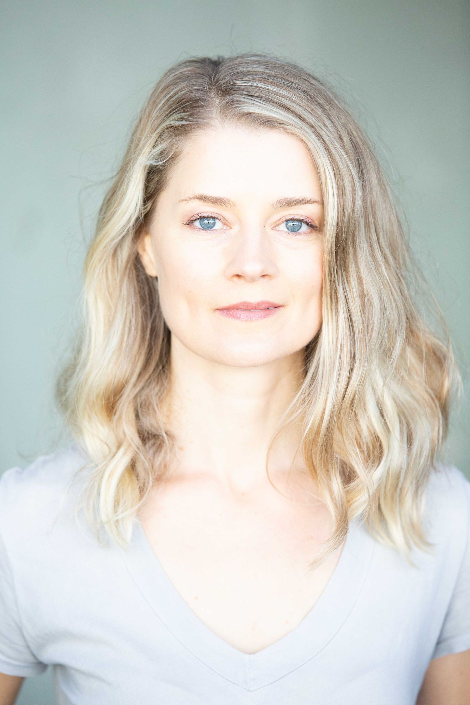 Professional headshot with soft lighting showing blonde wavy hair.