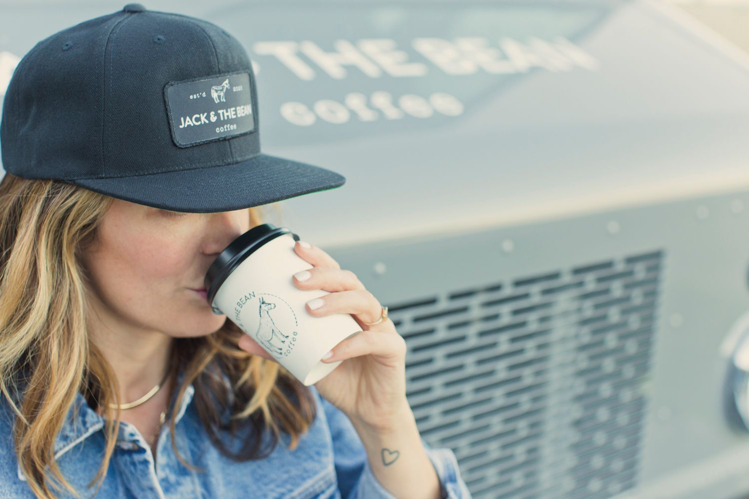 Coffee cup held near Jack & The Bean truck signage with cap visible.