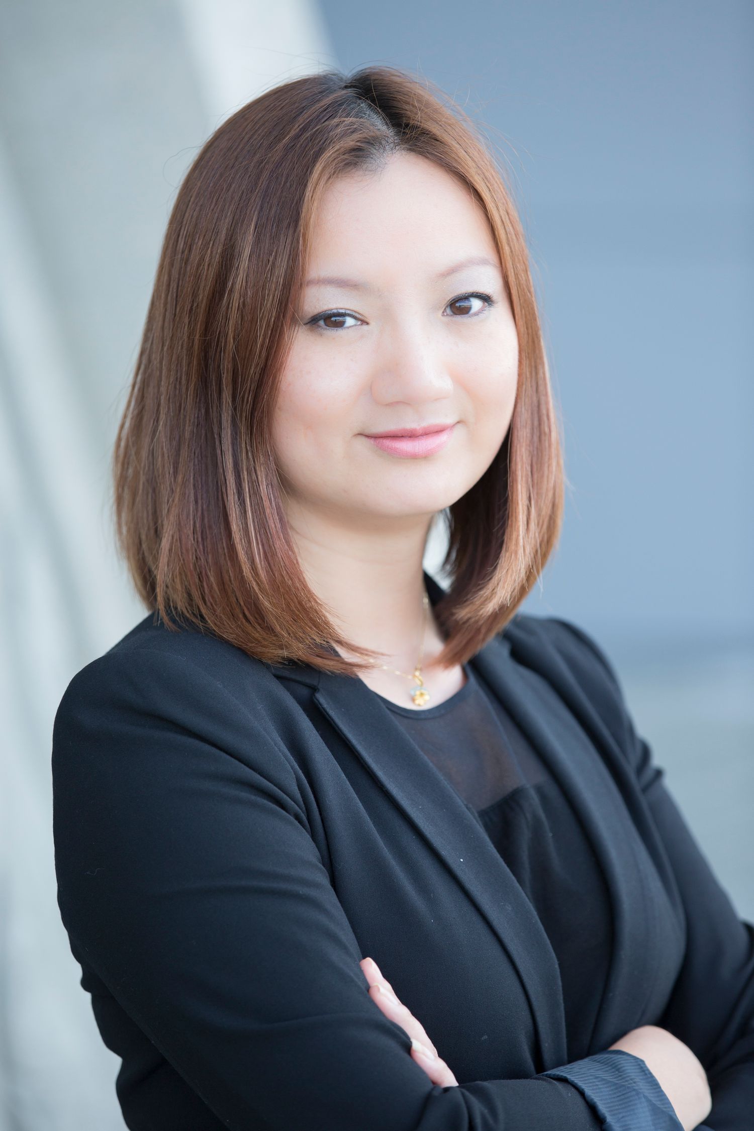 Professional headshots of person in black blazer against blue background.