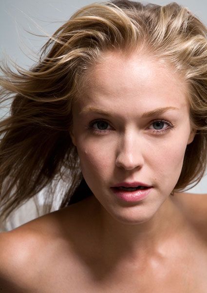 Beauty portrait with windswept blonde hair against neutral backdrop.