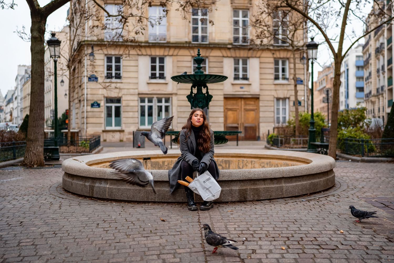 Casual portrait by a Parisian fountain with pigeons and classic architecture in the background.
