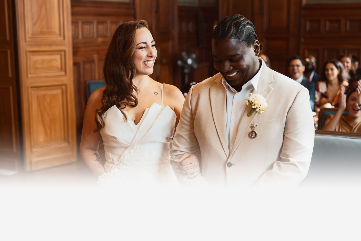 A joyful bride and groom share a candid moment during their wedding ceremony in an elegant wood-paneled venue.