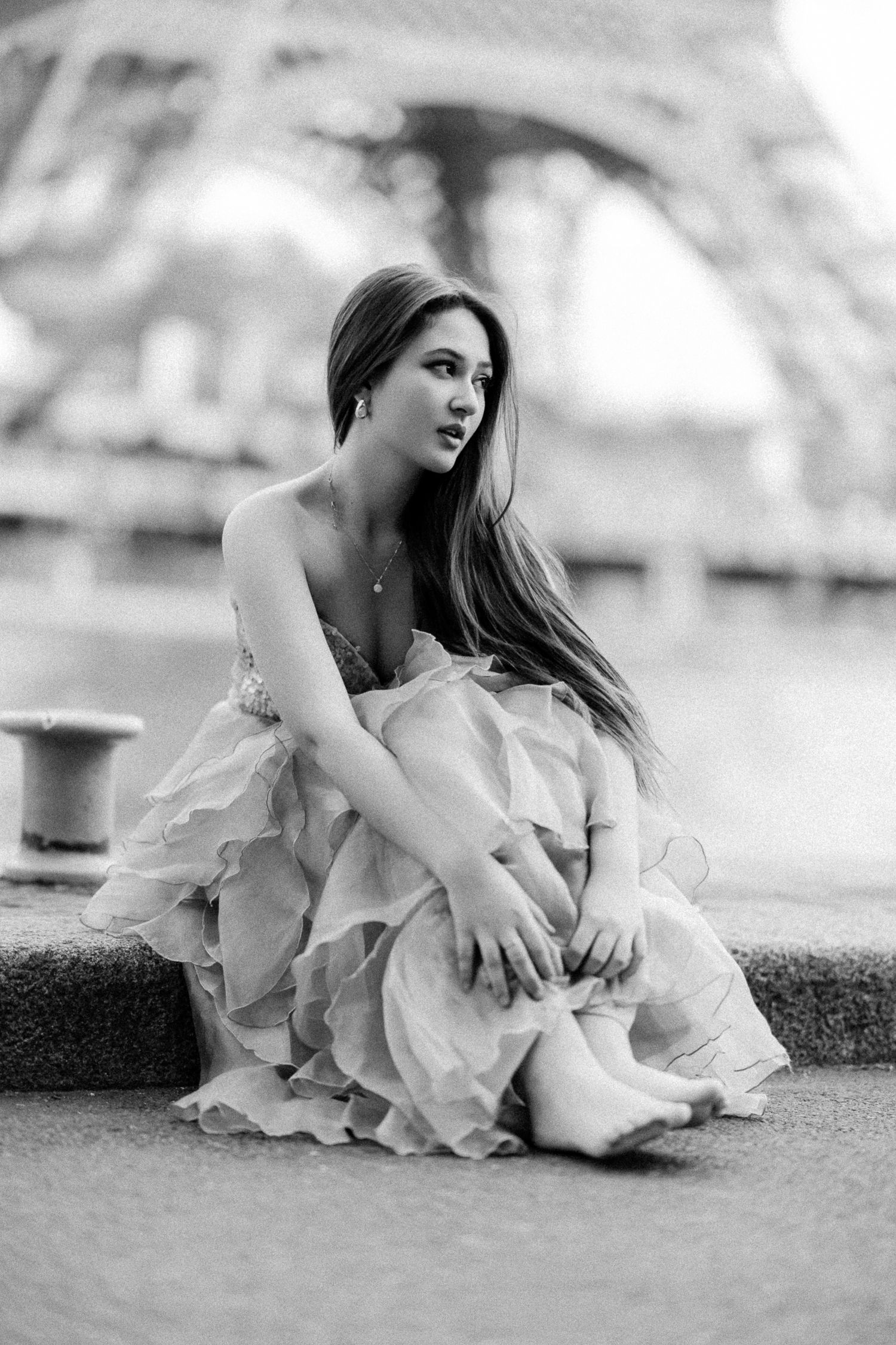 Artistic black and white portrait of a model in a flowing dress by the Eiffel Tower.