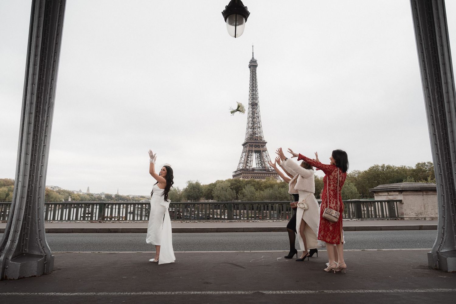 People in elegant outfits pose and dance on Bir Hakeim bridge with the iconic Eiffel Tower in the background in Paris.