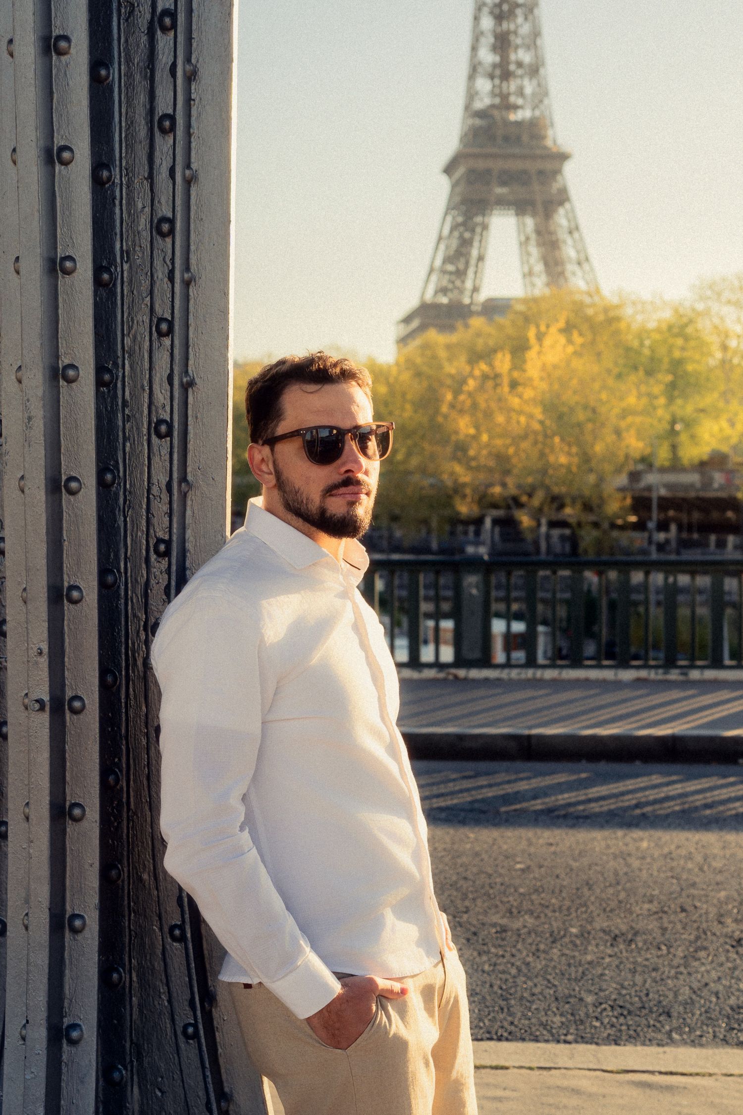 Person in white sweater poses against railing with Eiffel Tower backdrop in Paris.