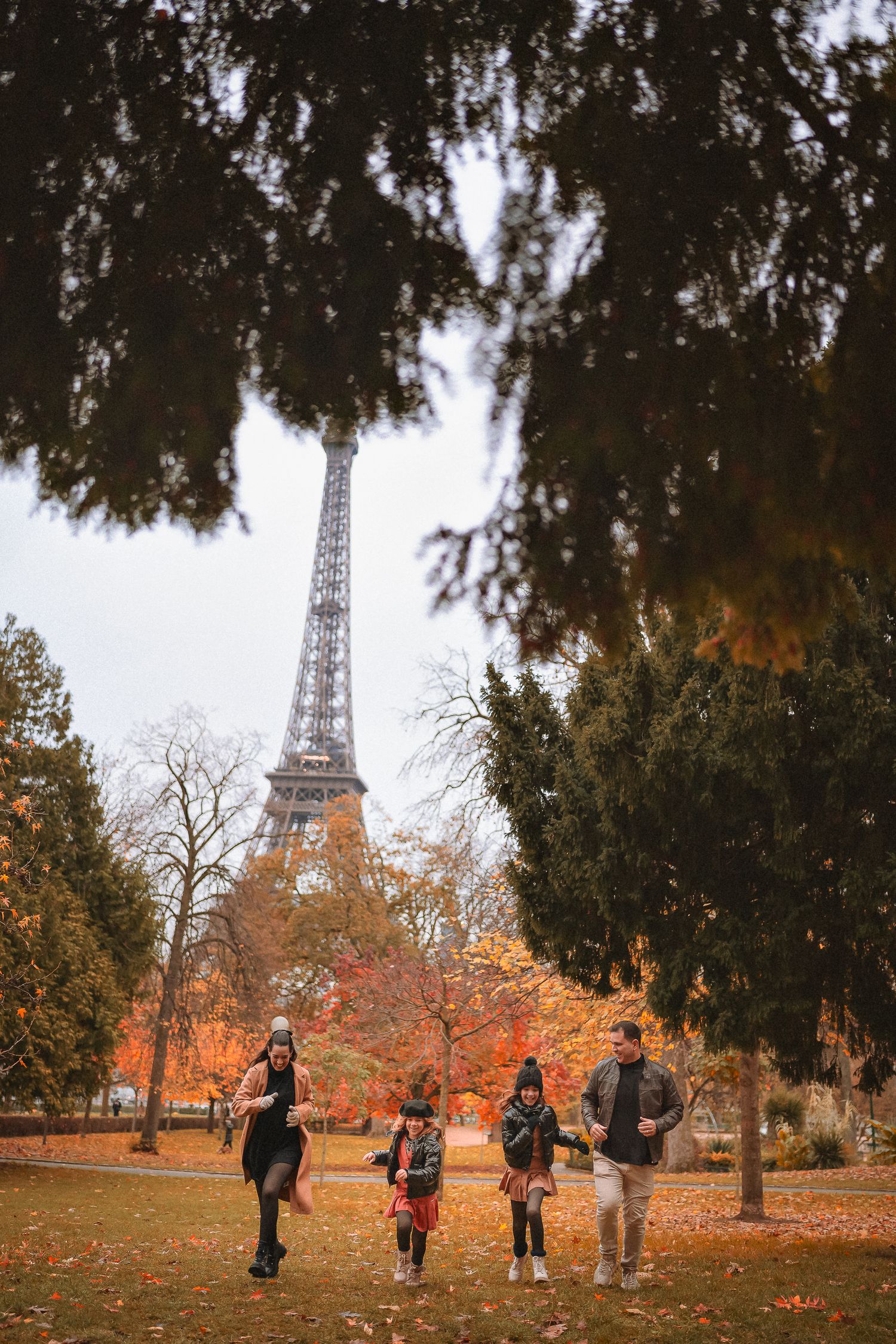 Family enjoying autumn stroll in park with Eiffel Tower vista.