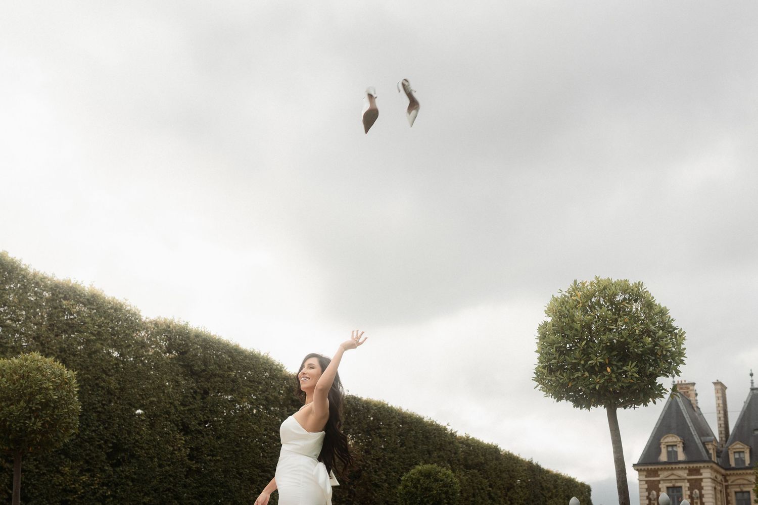 A wedding couple poses in front of a chateau in France during their outdoor countryside celebration.
