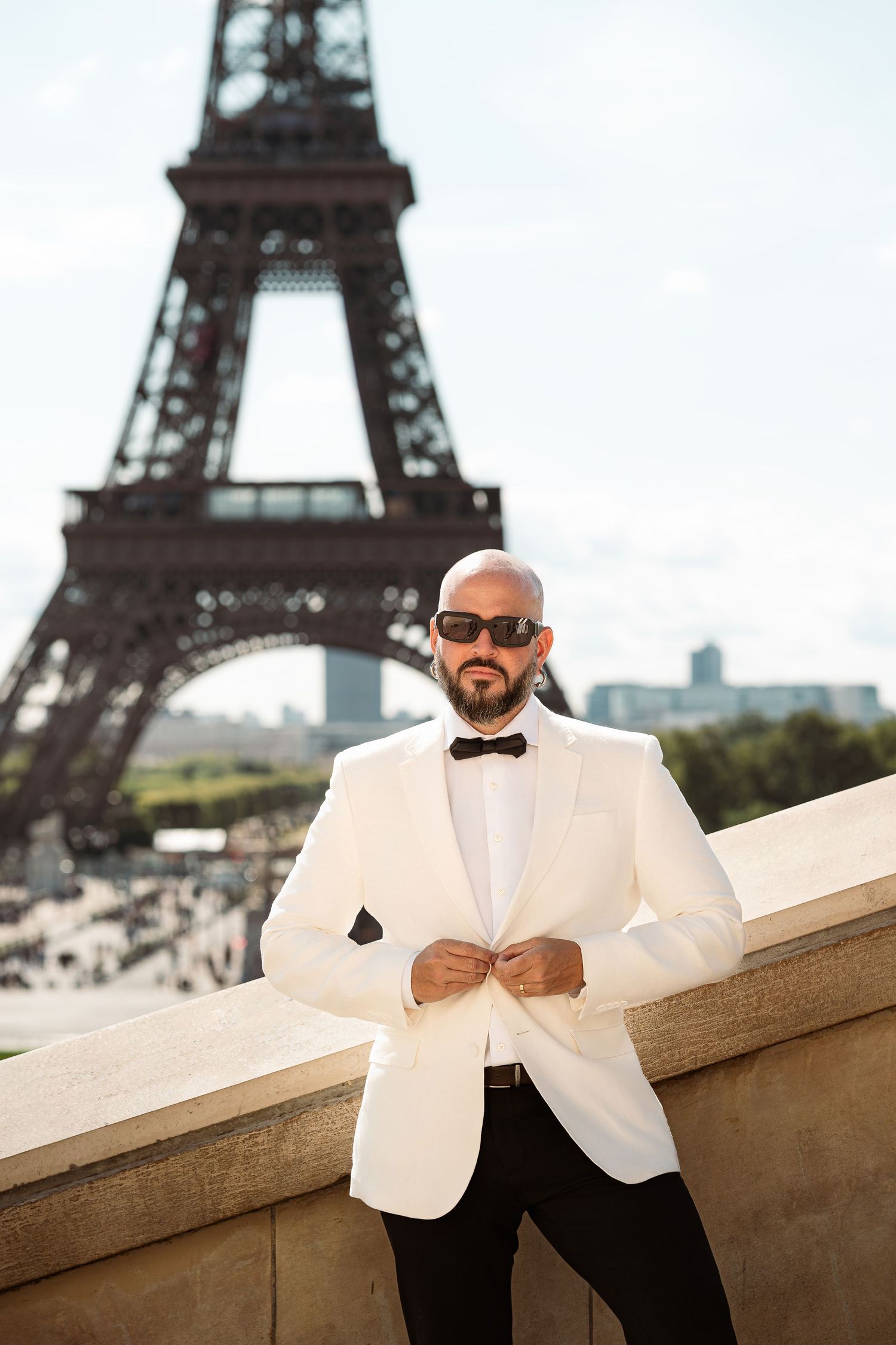 Stylish white tuxedo jacket and bow tie ensemble photographed in front of the iconic Eiffel Tower in Paris.
