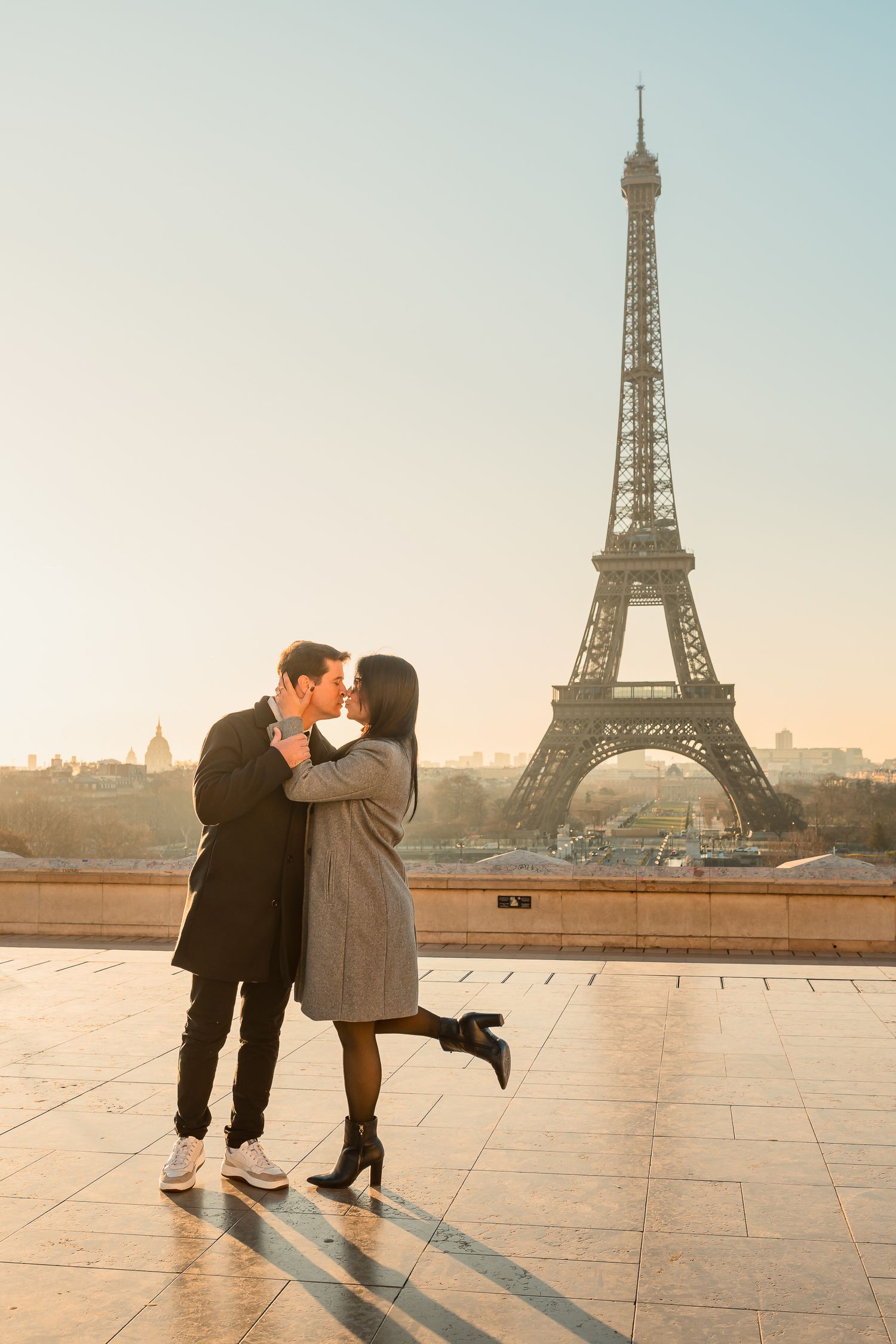 Romantic couple sharing a kiss at Trocadero with Eiffel Tower in background during sunset.