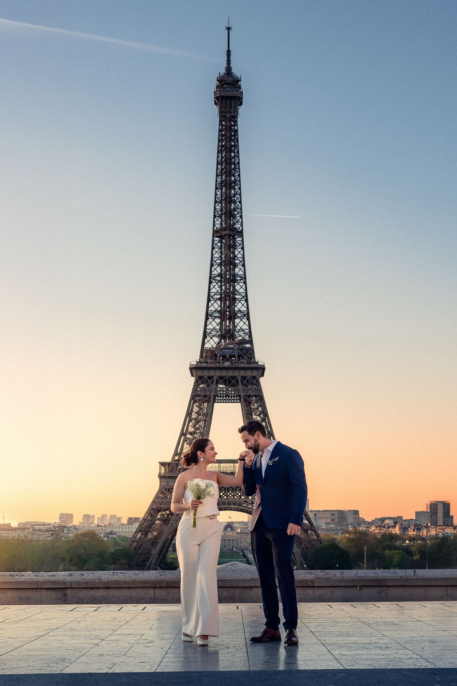 A romantic couple shares an intimate moment at sunrise with the Eiffel Tower creating a stunning backdrop in Paris.