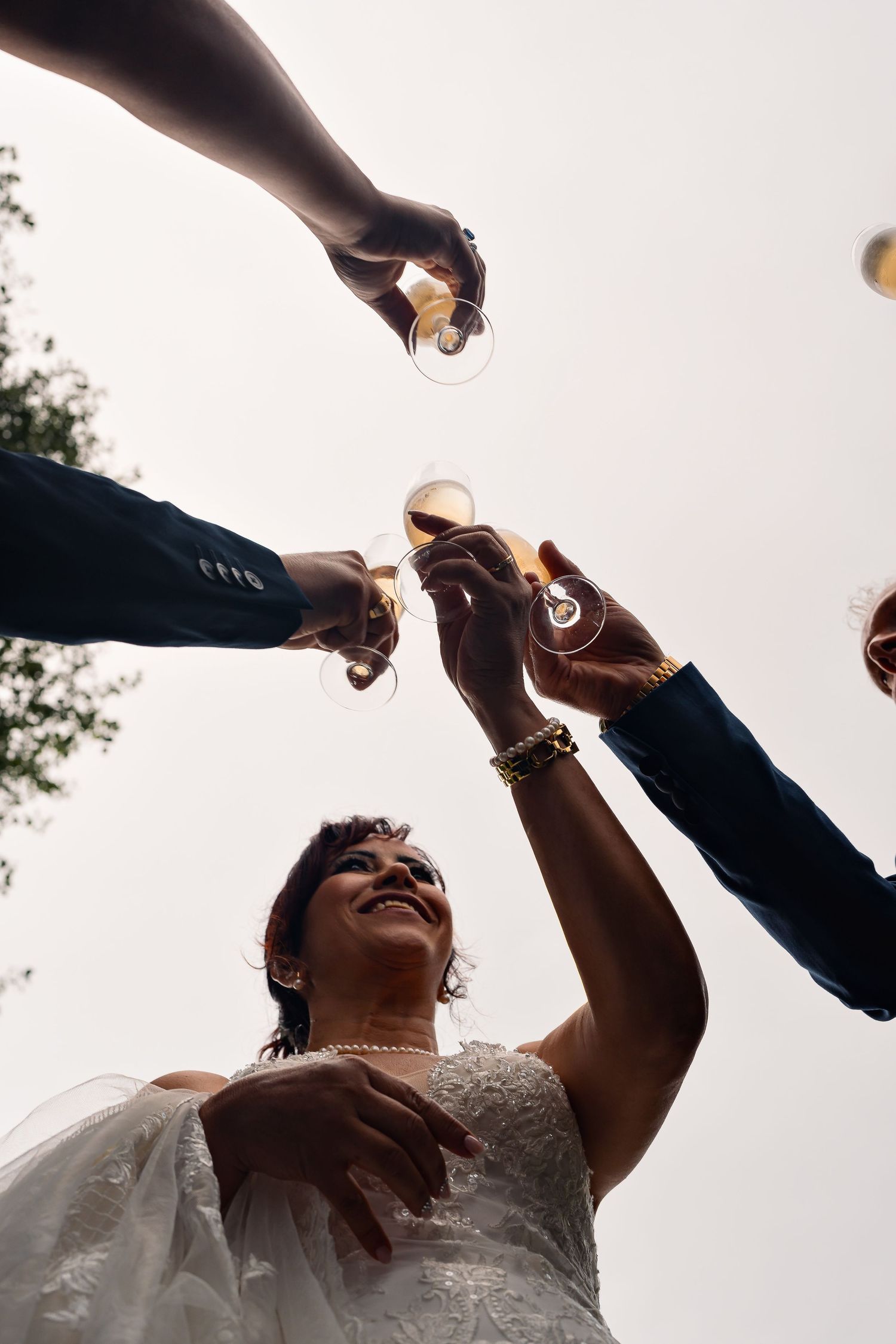 A person in white clothing drinks from multiple bottles being poured simultaneously at an outdoor celebration.
