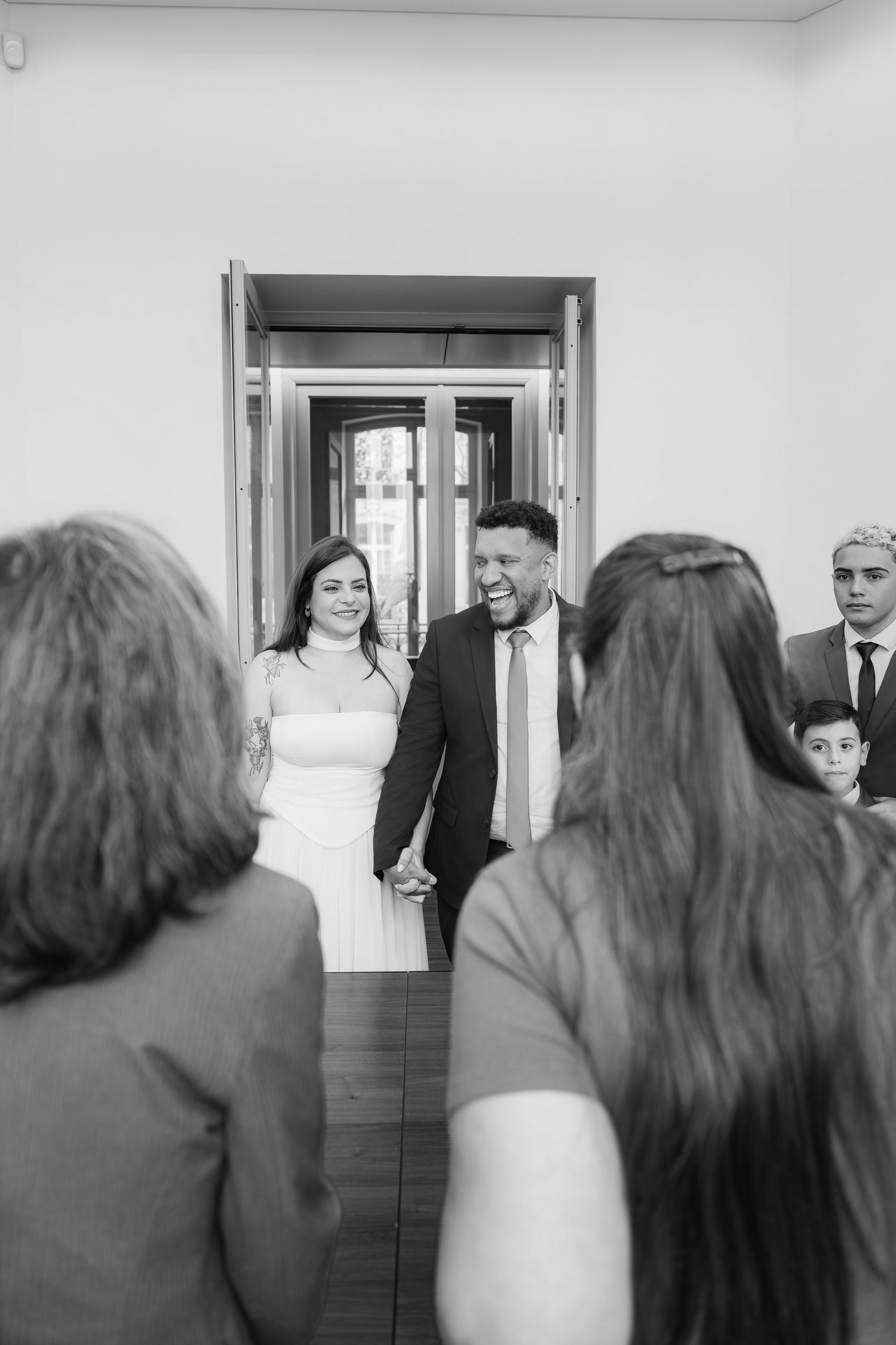 A series of black and white wedding photos showing a first look reveal moment between a bride and groom in a doorway.