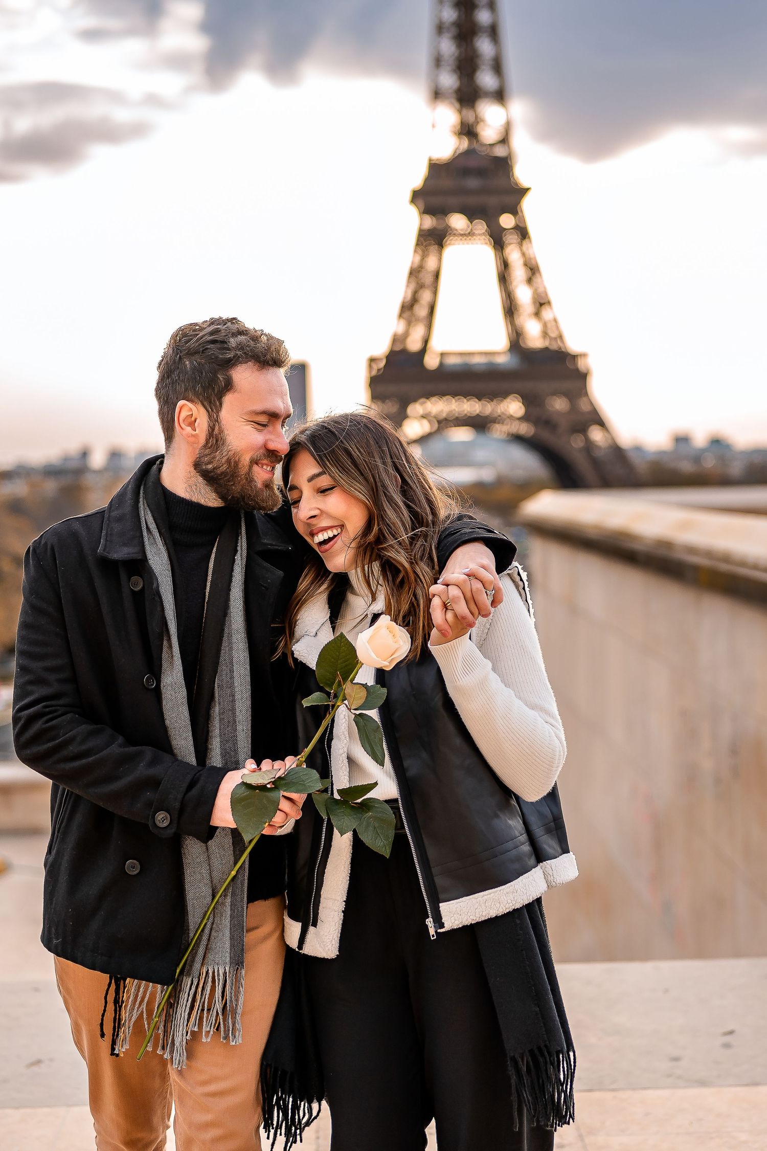 A romantic couple shares joyful moments in front of the Eiffel Tower during sunset in Paris.