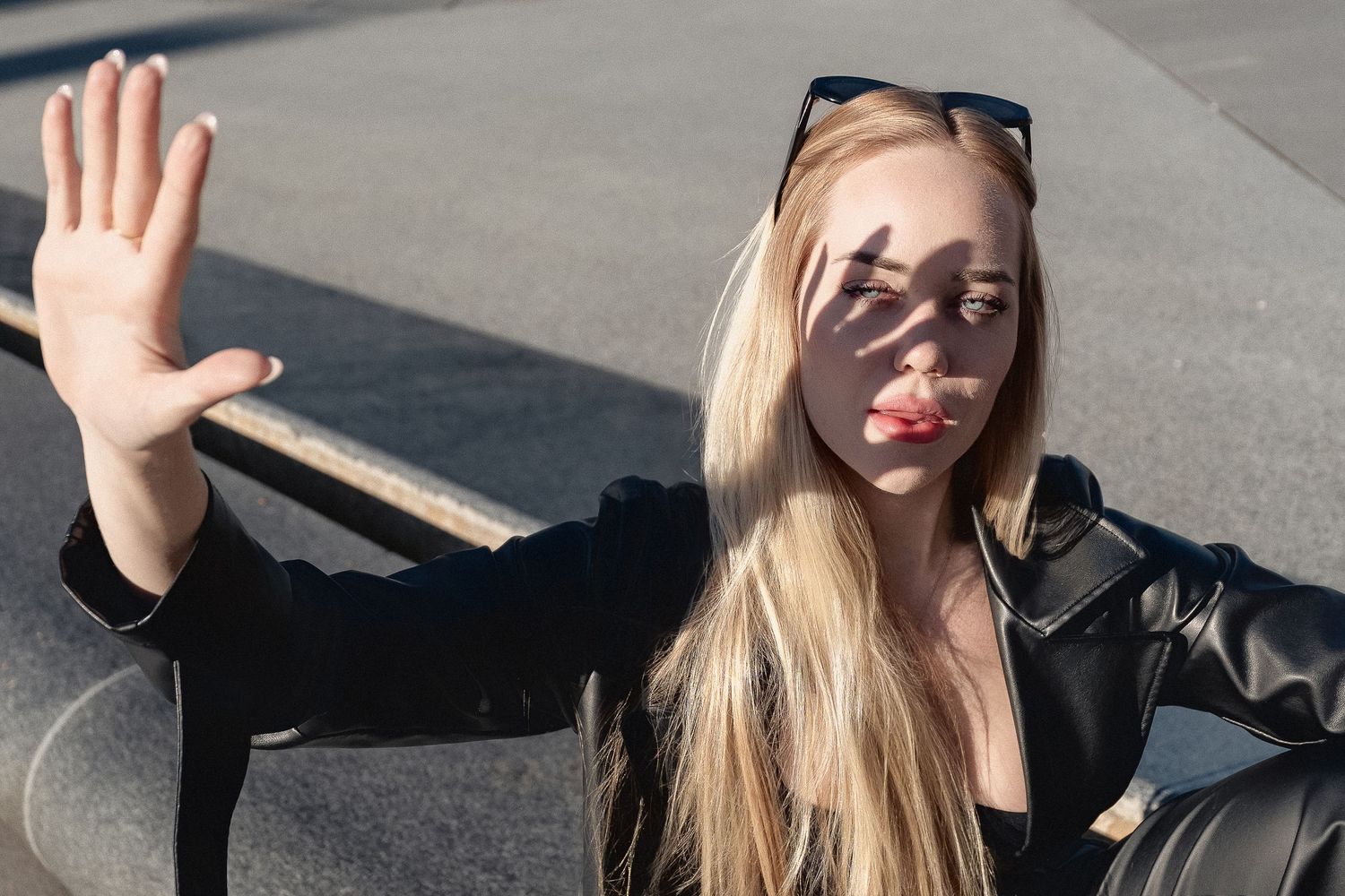 Person with blonde hair raising hand against sunlight in artistic portrait.