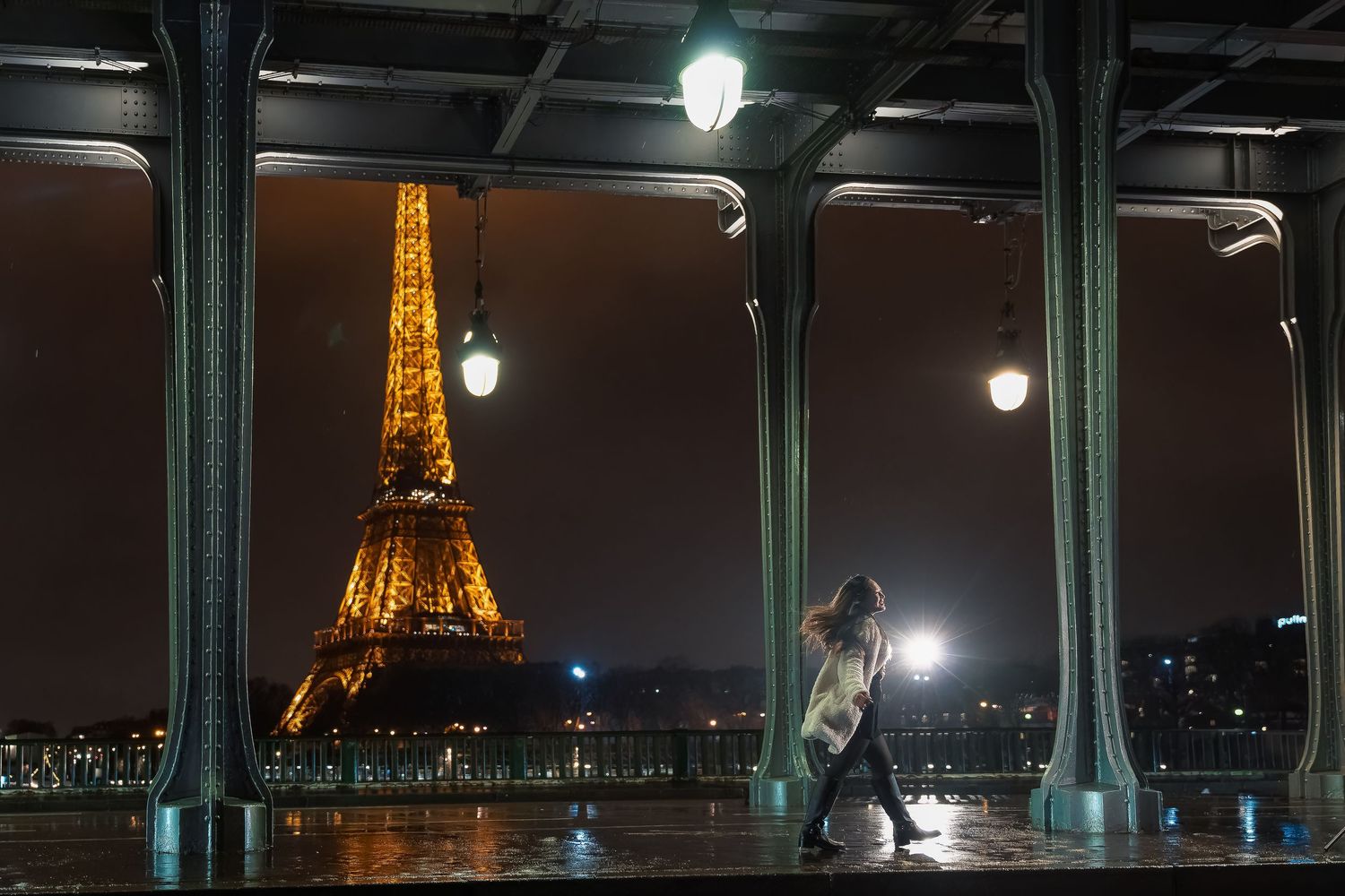 A silhouetted dancer performs beneath illuminated arches with the glowing Eiffel Tower in the background.