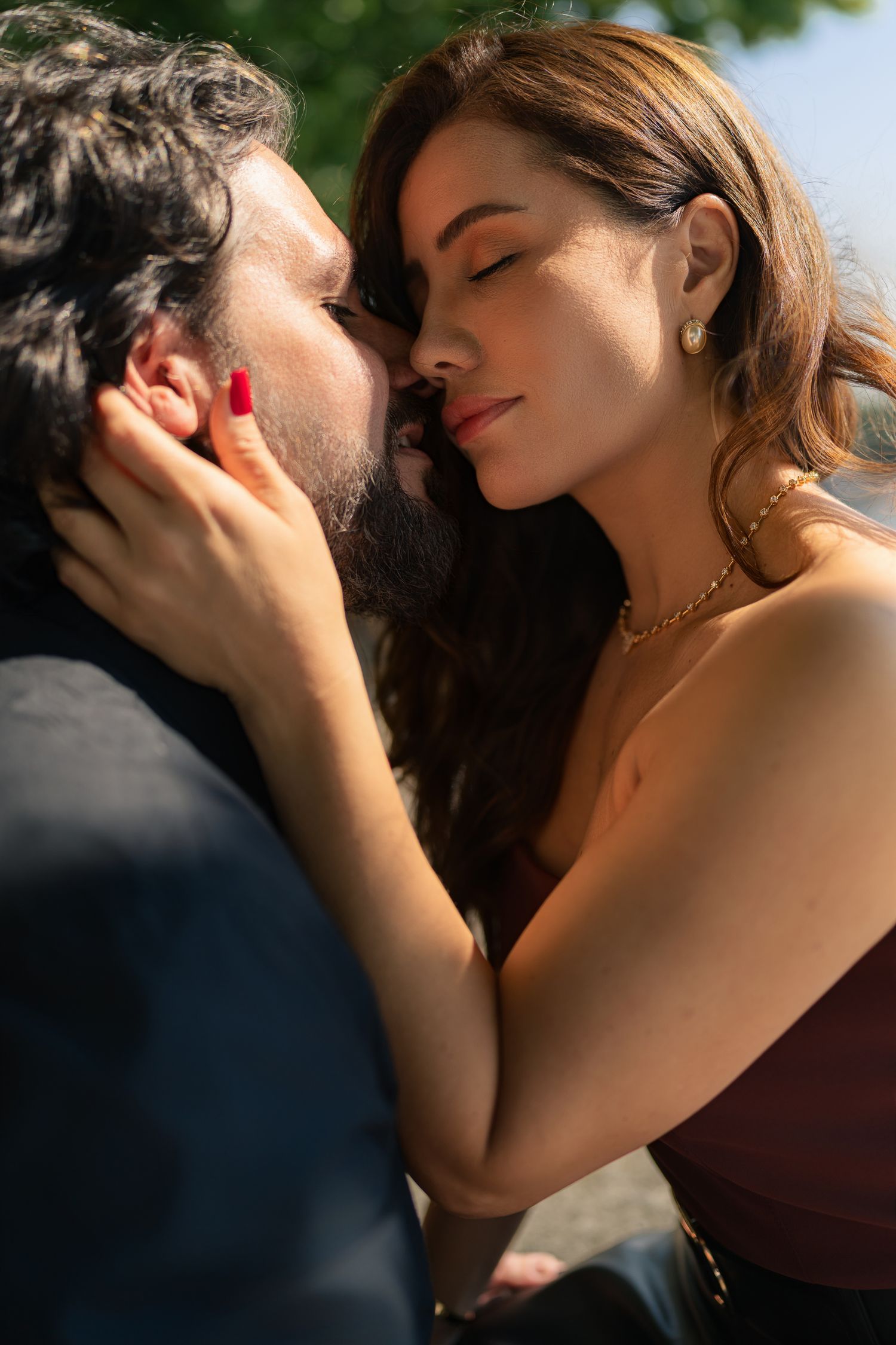 Intimate portrait of couple sharing tender moment in sunlit garden setting.