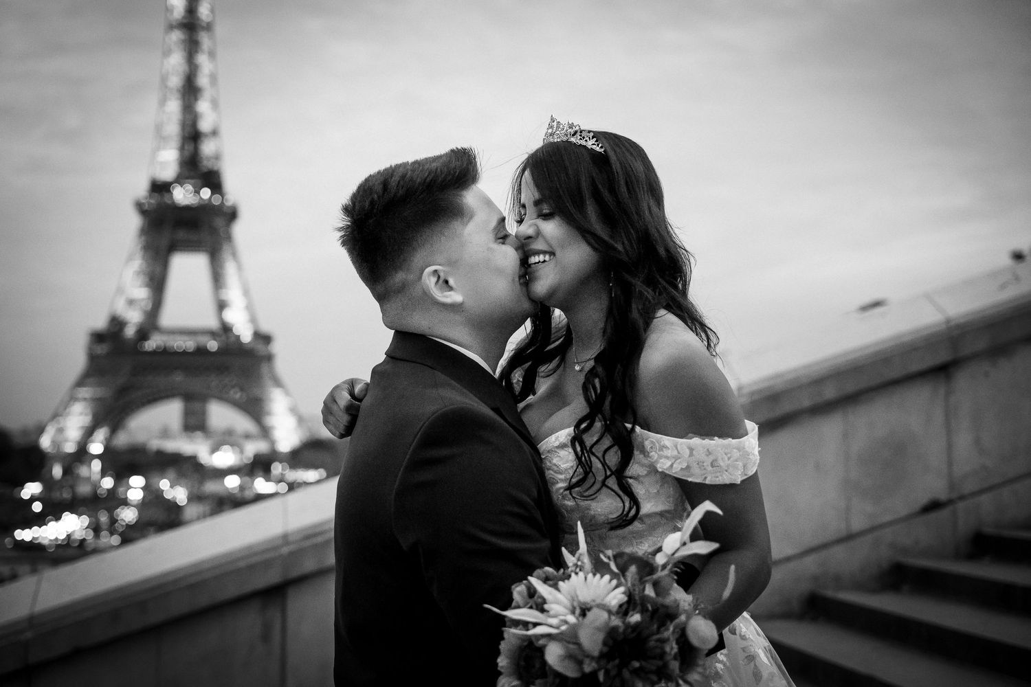 Newlyweds sharing a tender moment with Eiffel Tower backdrop in monochrome.